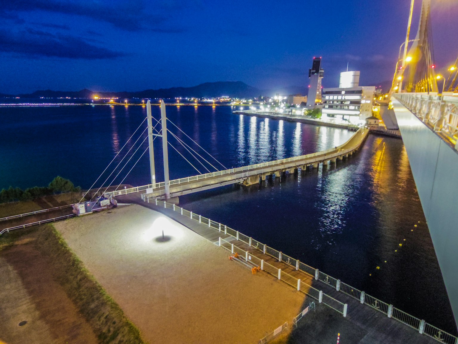 Eine schöne Hängebrücke über das Meer bei Nacht mit umliegenden Stadtlichtern