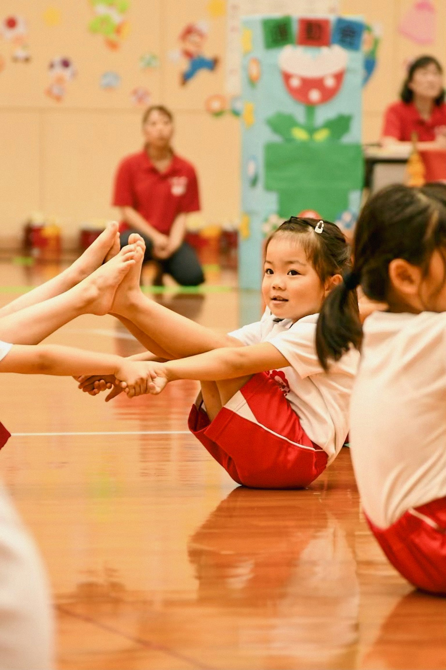 Des enfants pratiquant la gymnastique dans une salle de sport Une fille en uniforme rouge prenant une pose Décorations colorées en arrière-plan