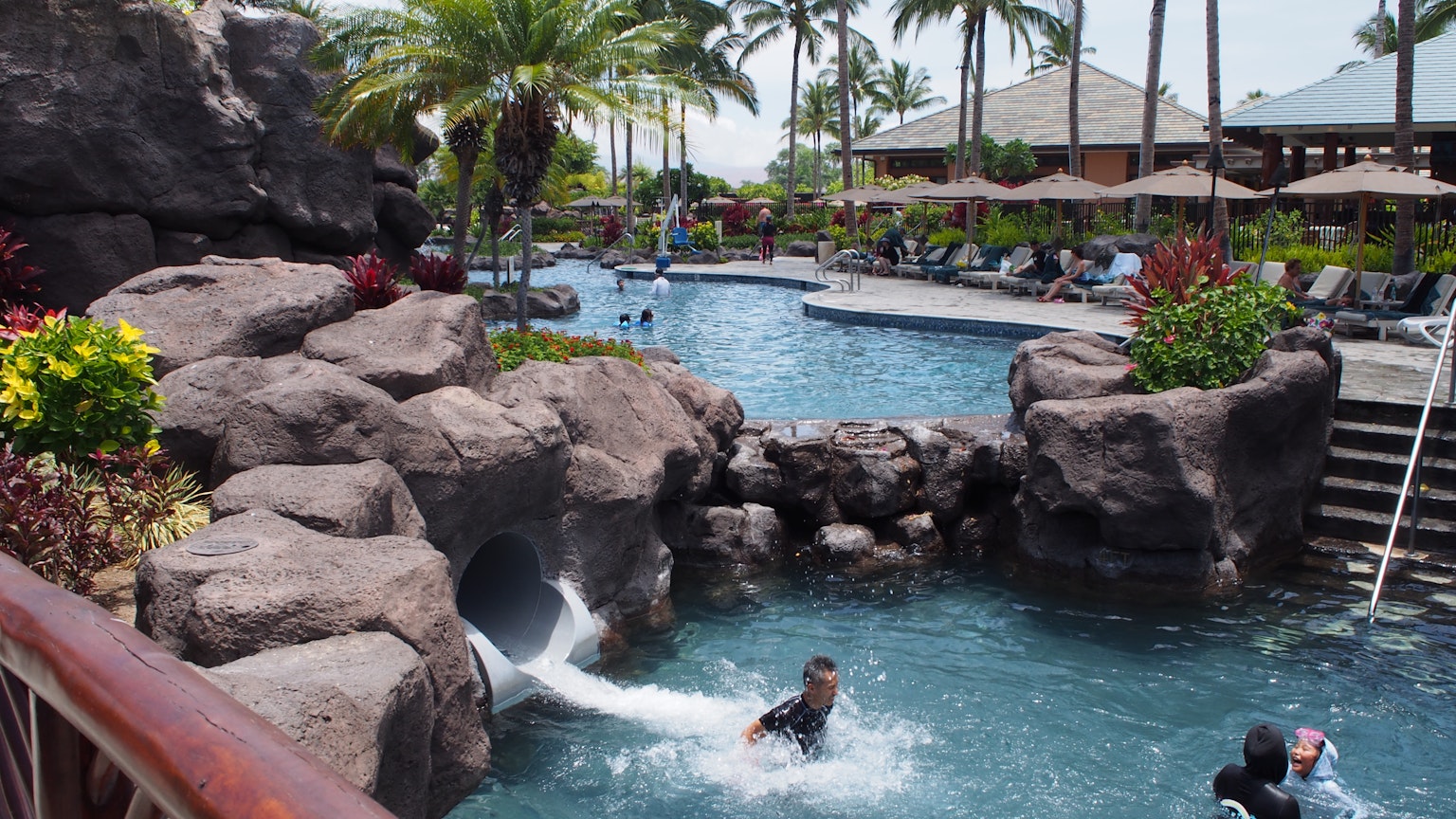 Scena di resort con piscina blu e scivolo di roccia