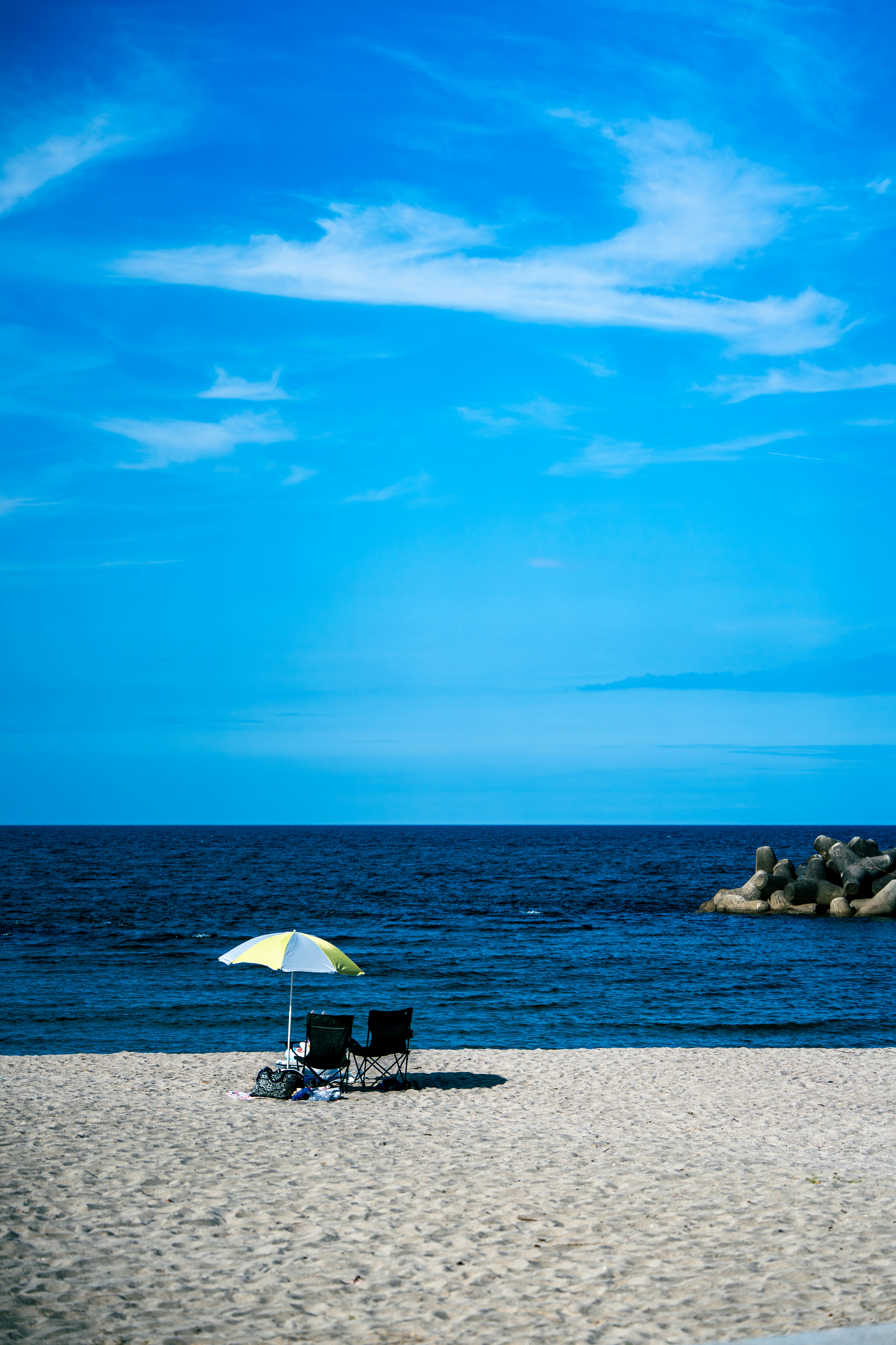 海邊沙灘與藍天，帶遮陽傘的休憩點