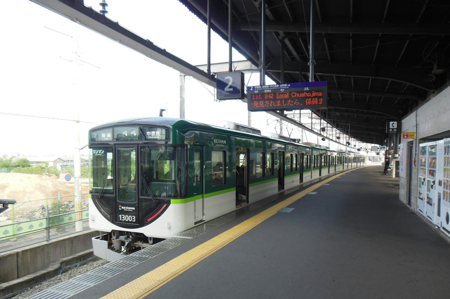 Sebuah kereta hijau dan putih berhenti di stasiun