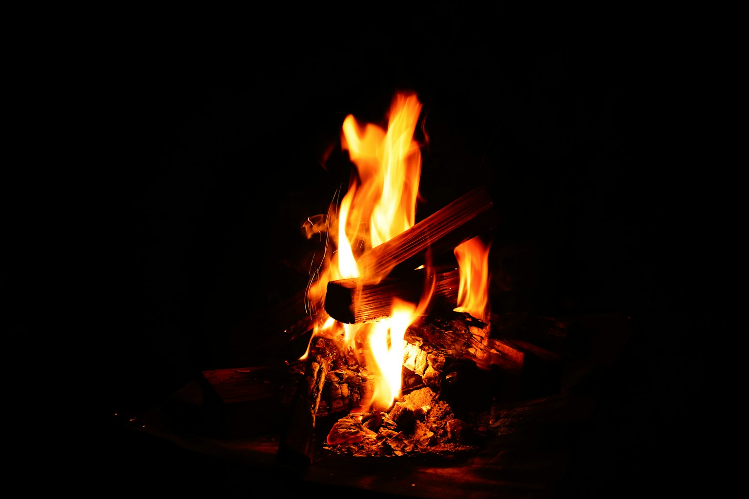 Fiamma di un falò con tronchi che bruciano nel buio
