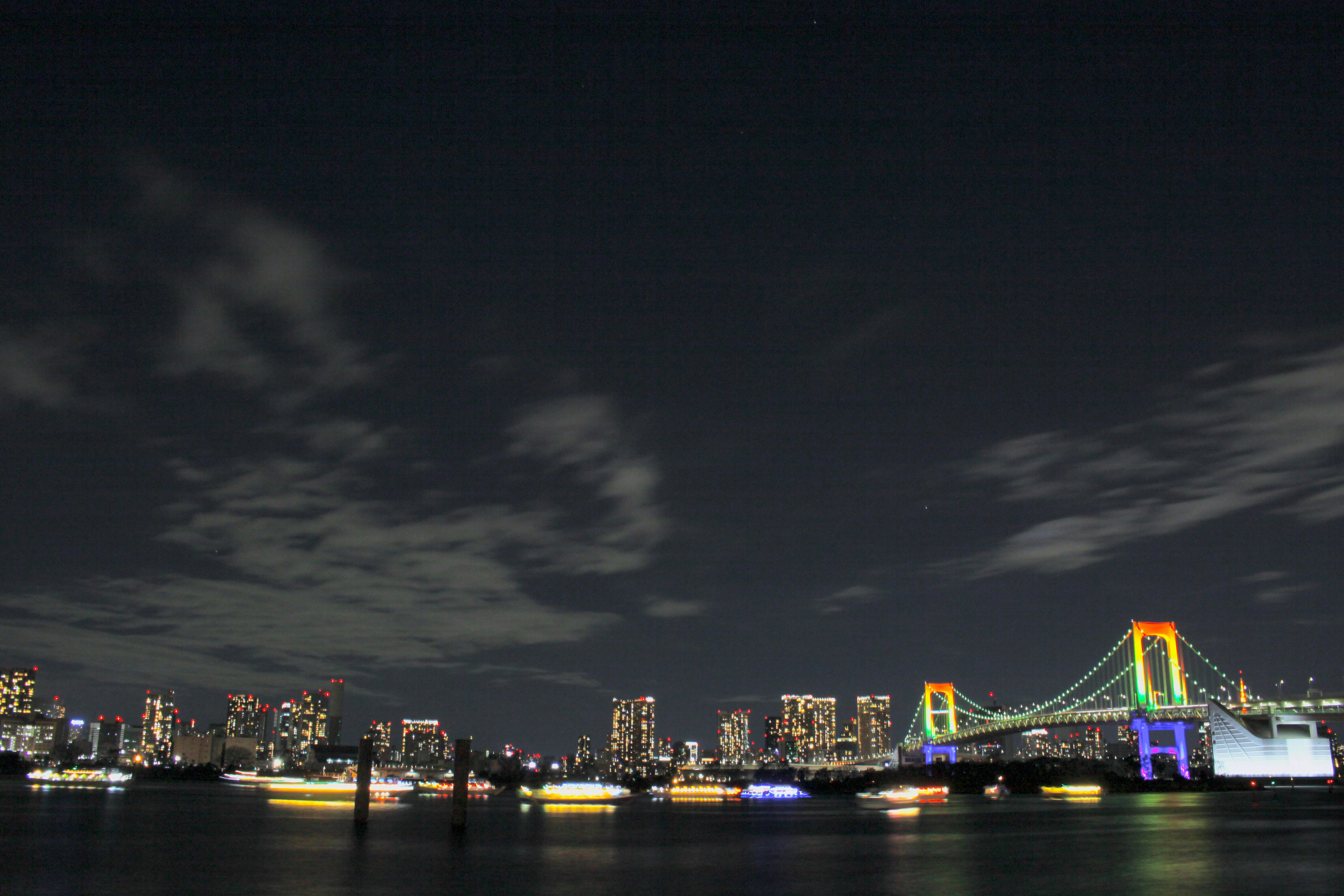 夜の港に浮かぶ遊覧船と対岸の高層ビル群