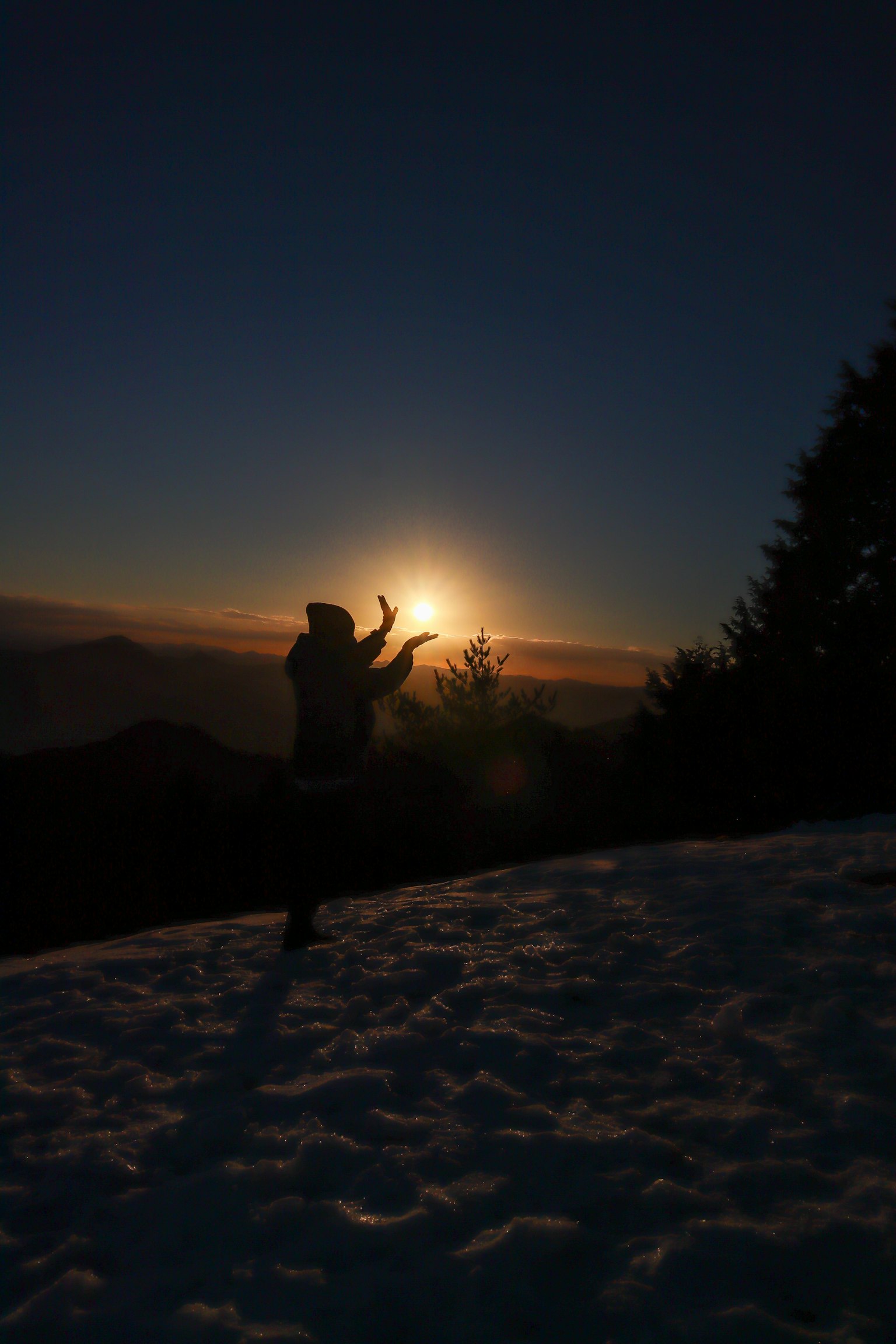 Silueta de una persona posando sobre la nieve con el amanecer de fondo