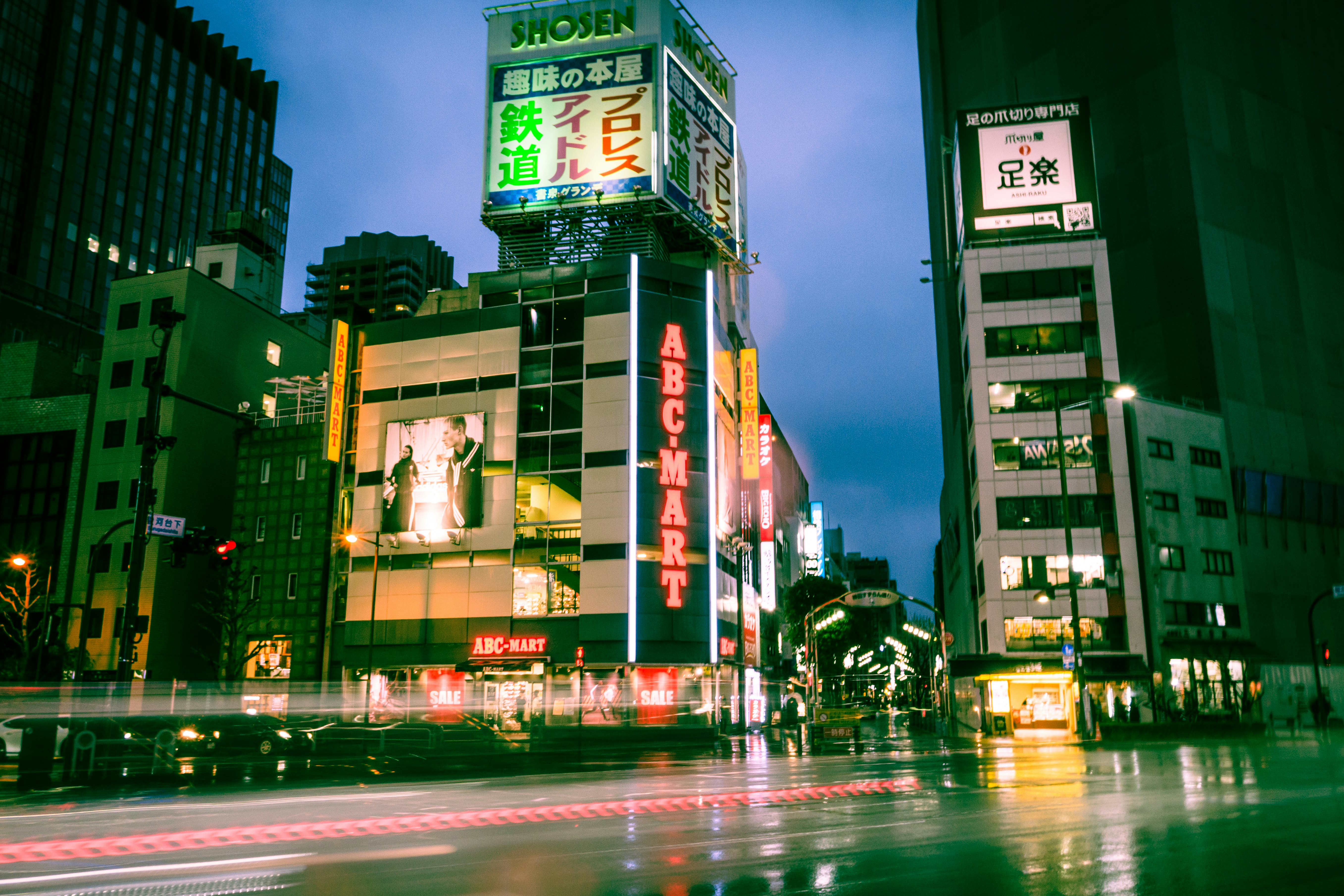 雨の交差点に立つネオン看板のある東京の街並み