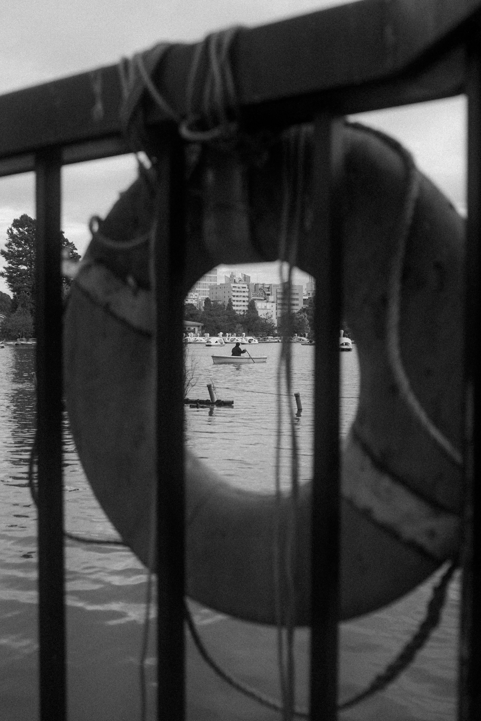 Boya en blanco y negro enmarcando una vista del agua con botes a lo lejos
