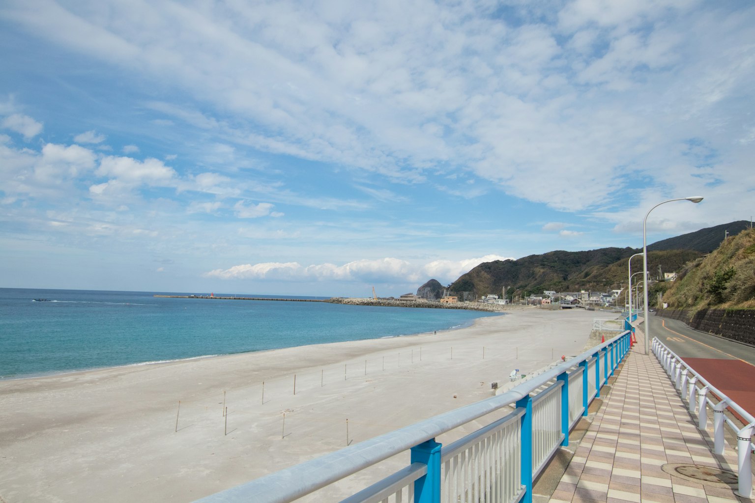 Panoramablick auf einen Strand mit blauem Ozean und Himmel gepflasterter Gehweg und weißer Sandstrand