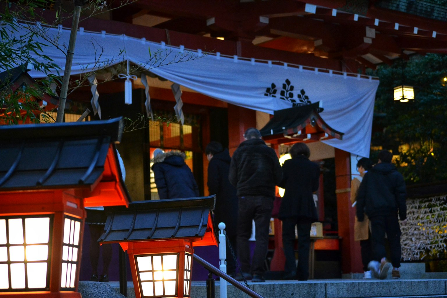 人们走向一个有红色灯笼的神社入口