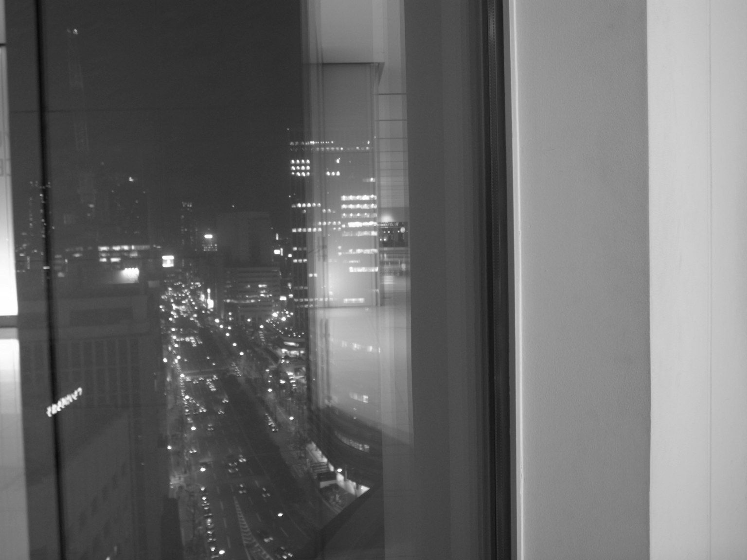 Vue nocturne d'une fenêtre montrant un paysage urbain Lumières urbaines en noir et blanc et circulation