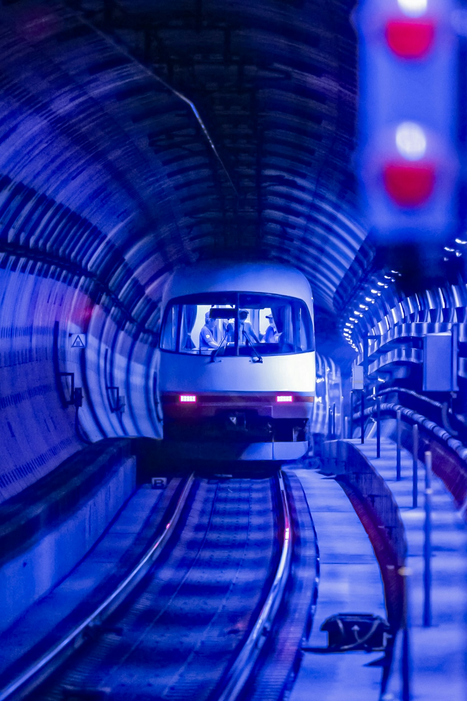 Zug, der in einen blauen Tunnel mit roten Signalen einfährt