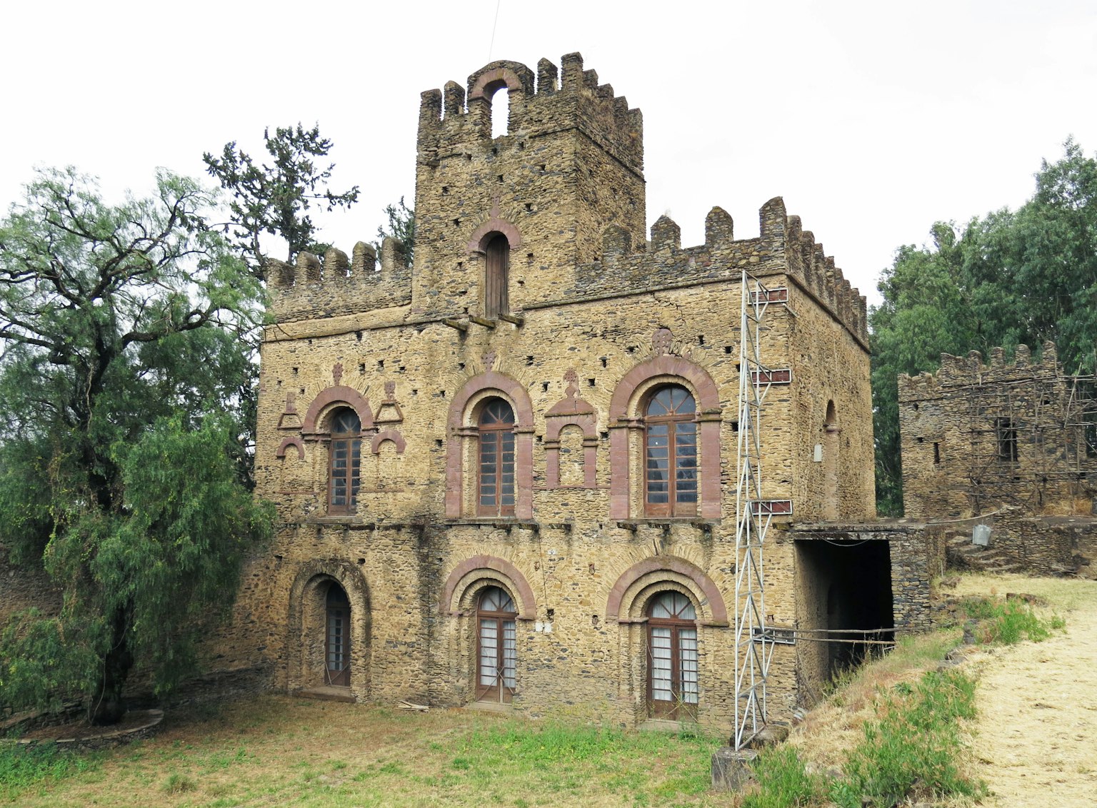 Antiguo edificio similar a un castillo rodeado de vegetación con paredes de piedra y torres