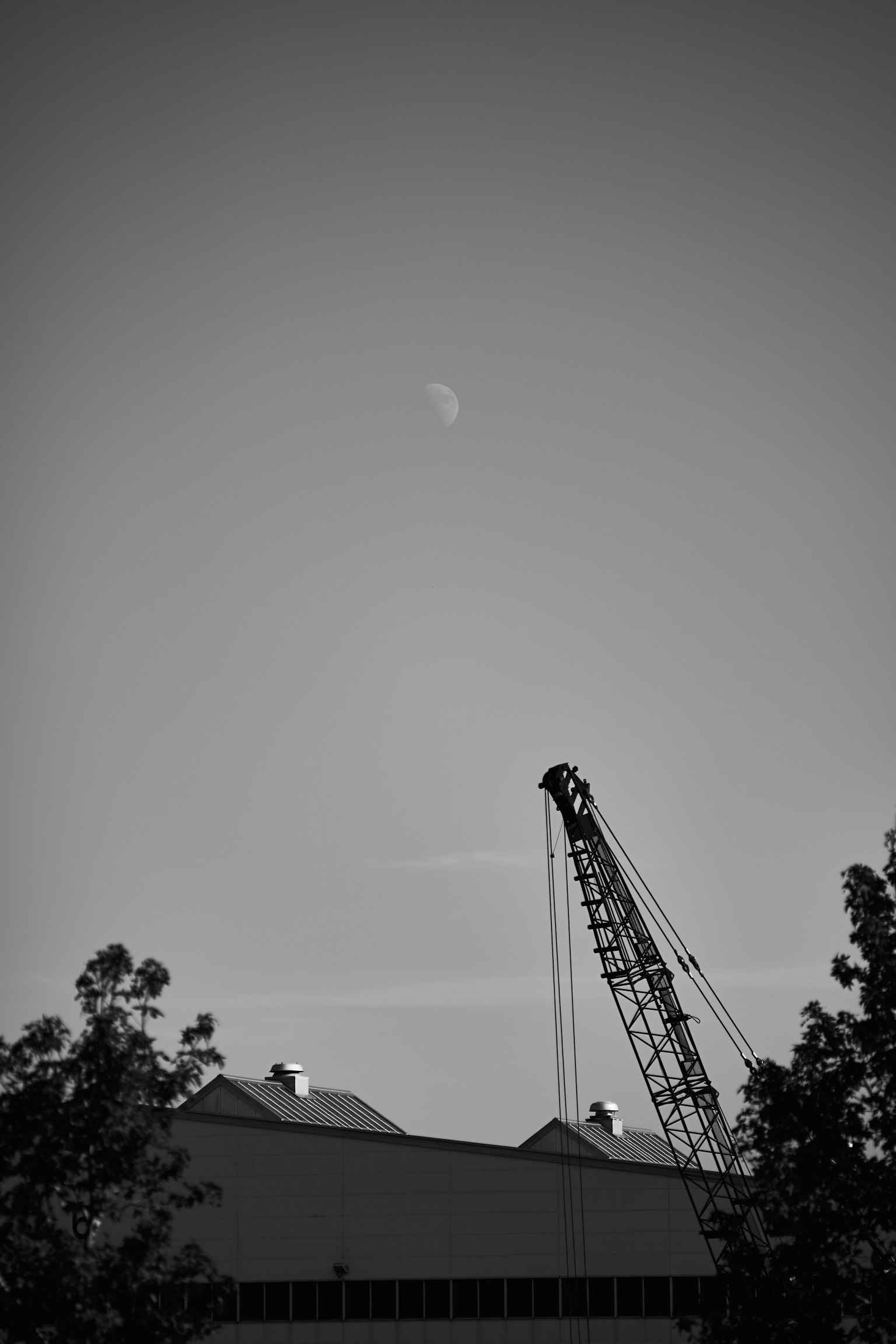 黒と白の空にクレーンと建物が見える