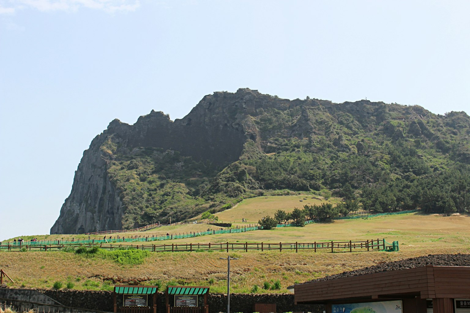 A rocky mountain with green hills under a blue sky