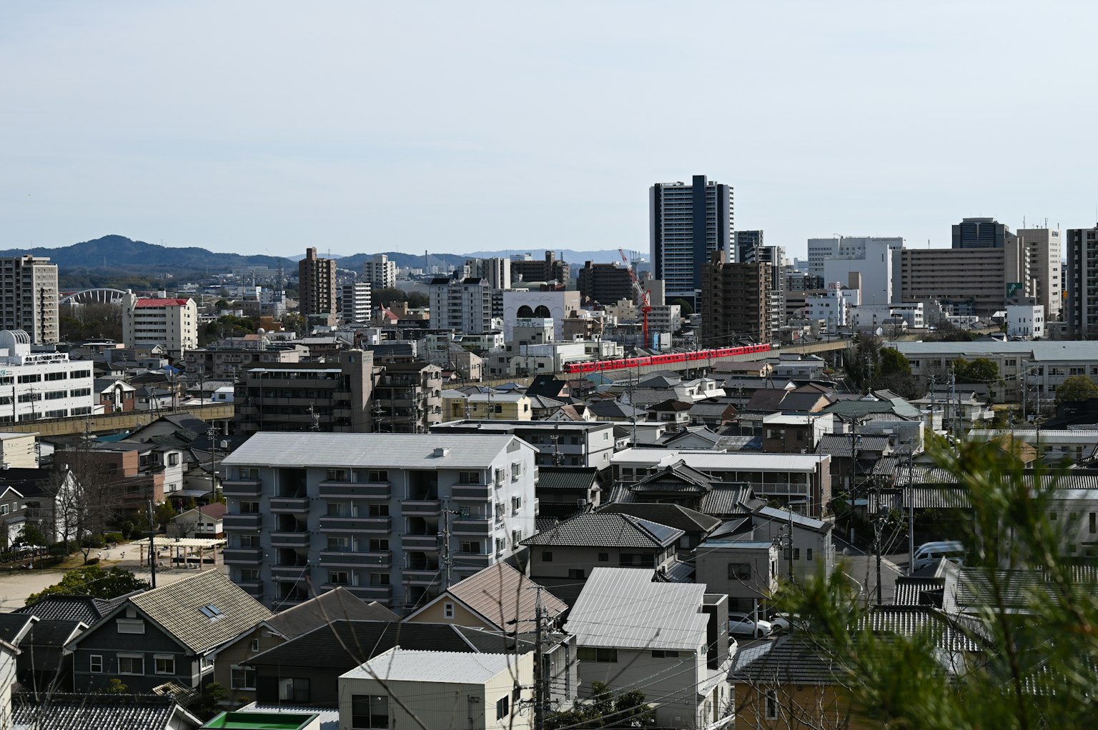 Cityscape showing a mix of buildings and houses with mountains in the background