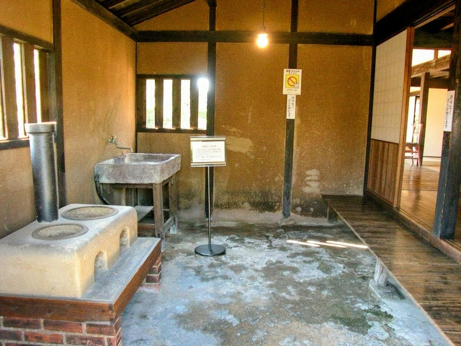 Interior de una casa japonesa tradicional con paredes de barro y vigas de madera, con un fregadero y un lavabo de piedra
