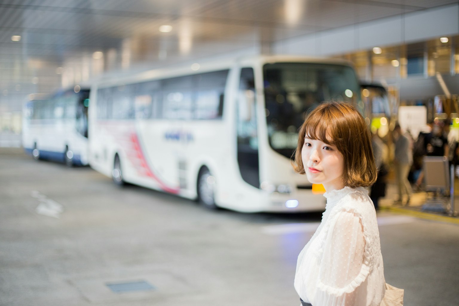 A woman standing near a bus with multiple buses in the background