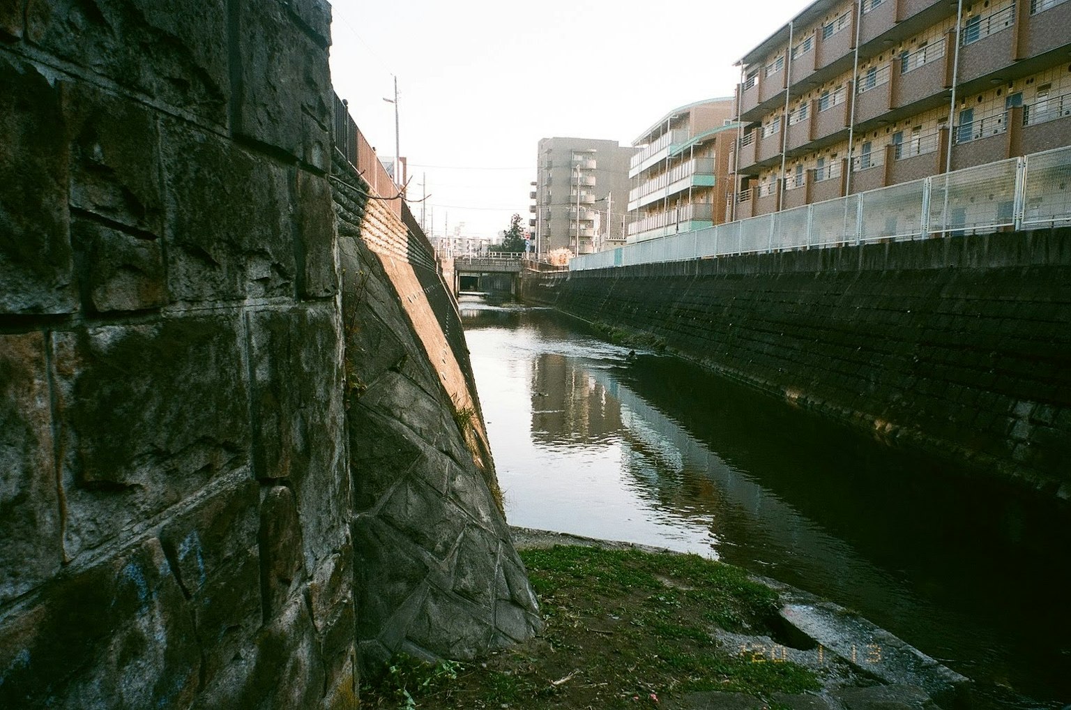 Narrow waterway with a stone wall and nearby apartment buildings