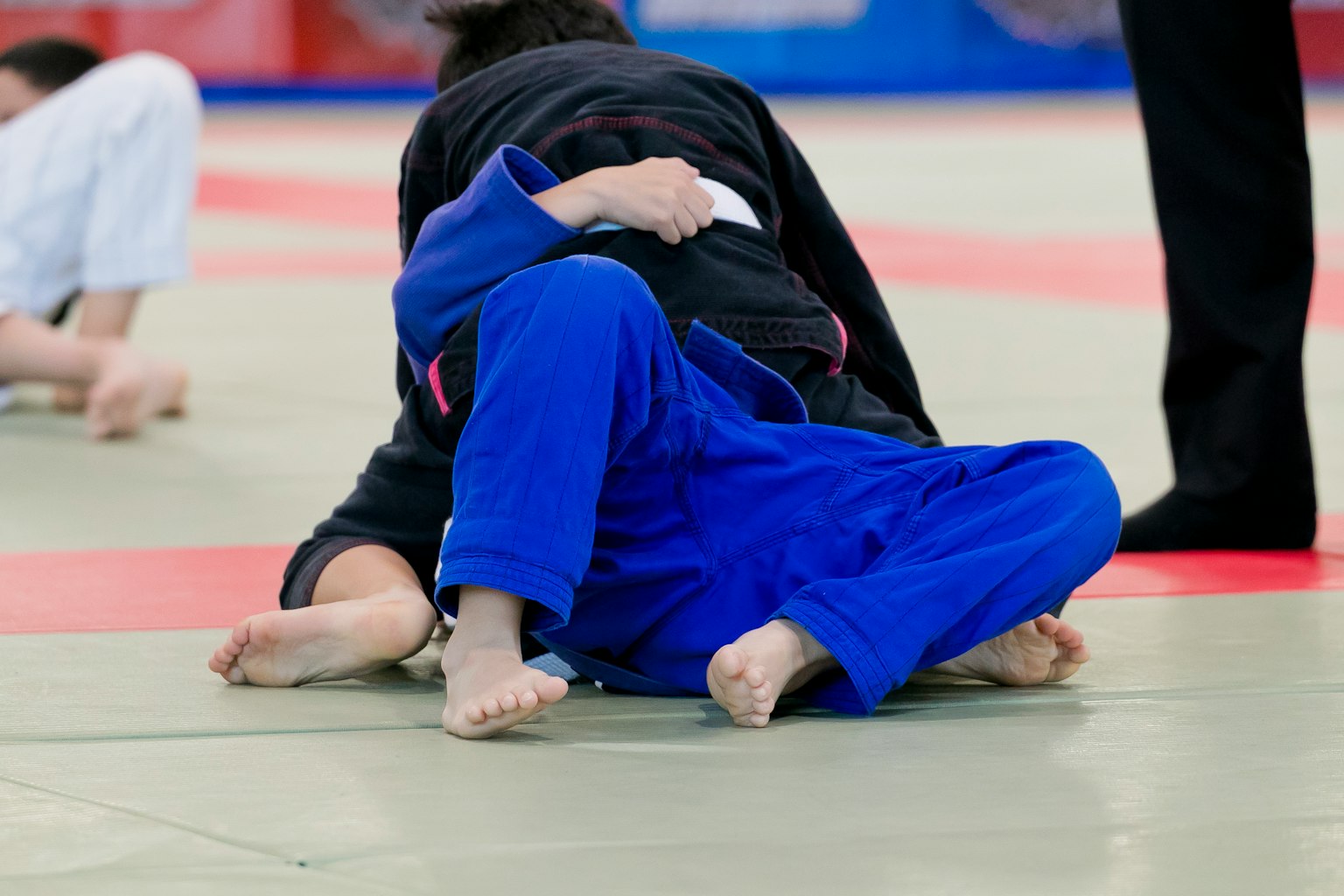 A judo match showing a competitor in a blue gi on the ground