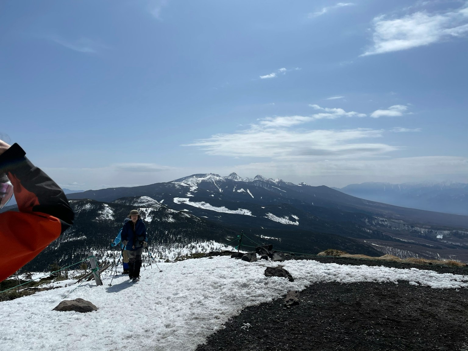 Wanderer auf einem verschneiten Bergweg mit Blick auf entfernte Berge