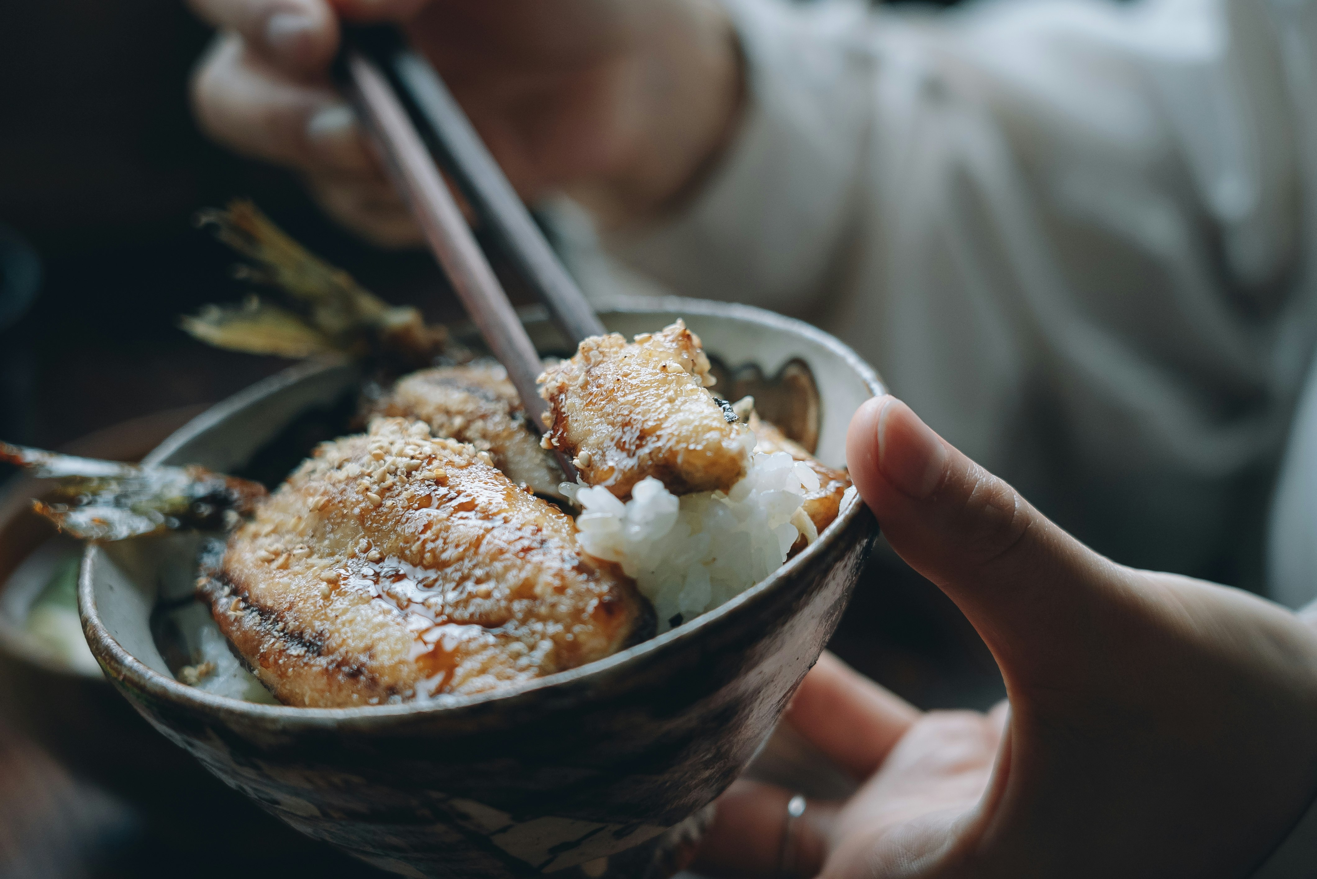 bacchette che prendono cibo fritto da una ciotola di riso