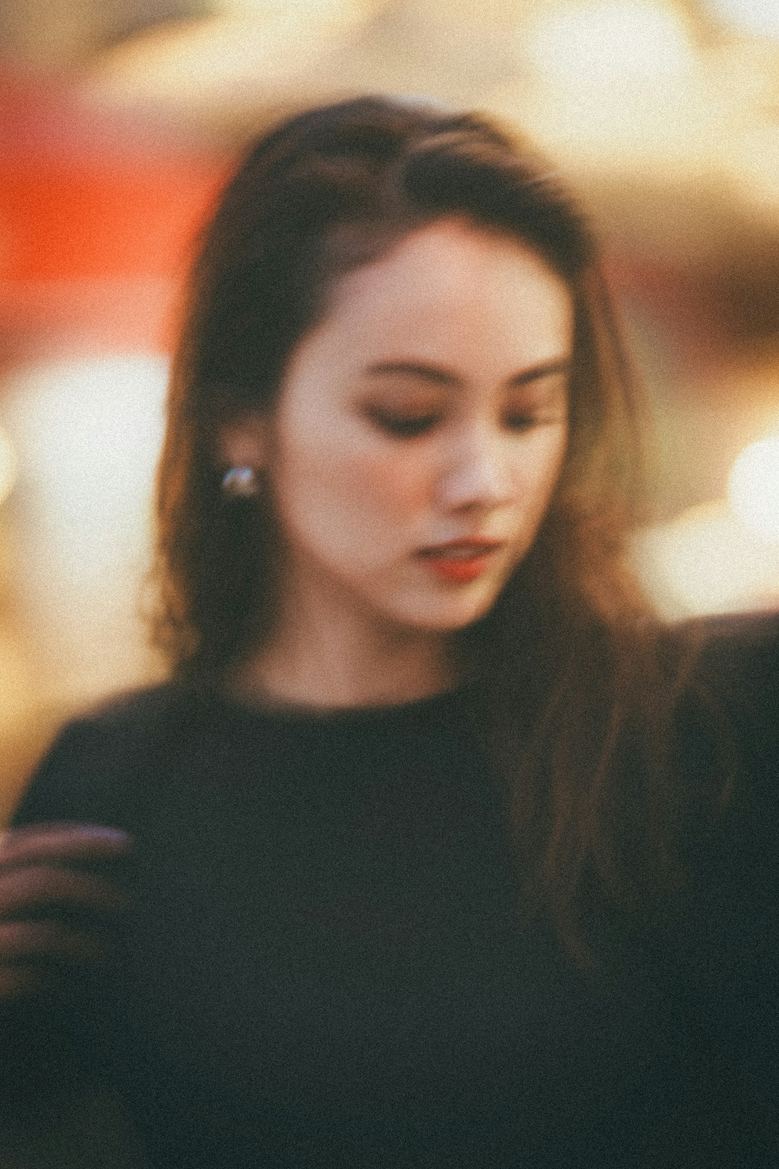 一位穿著黑色衣服的女性低頭，背景模糊