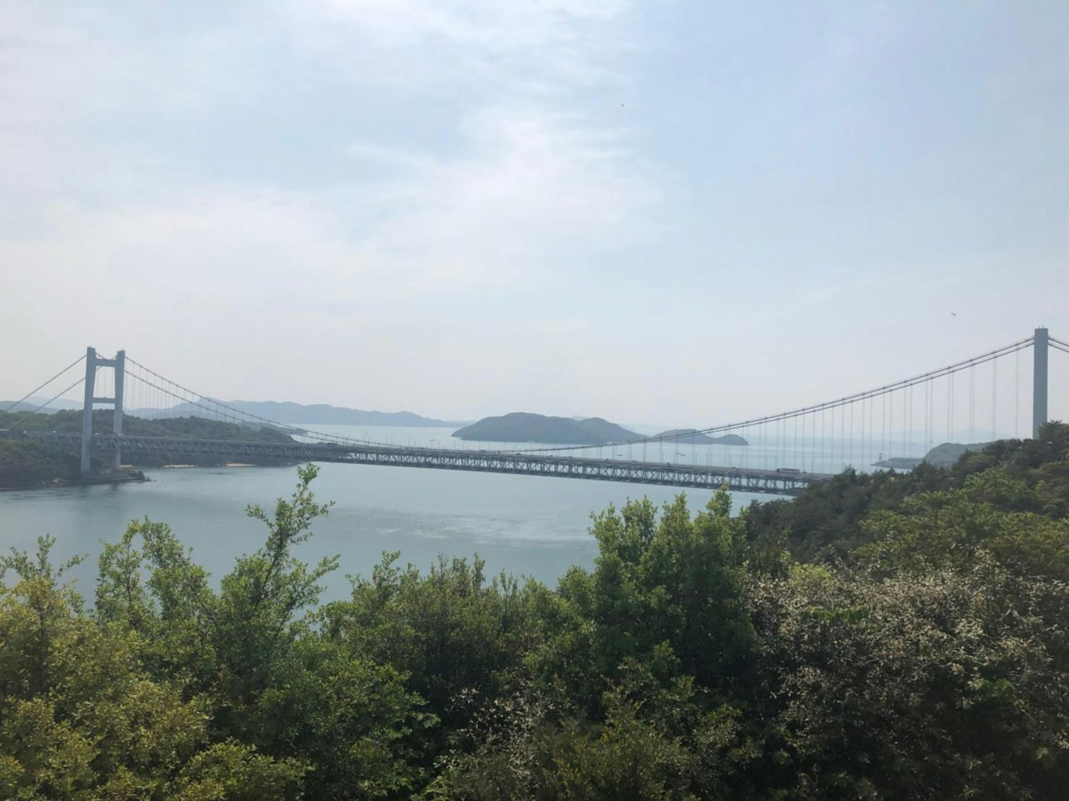 Scenic view of a bridge spanning a tranquil sea with islands in the background