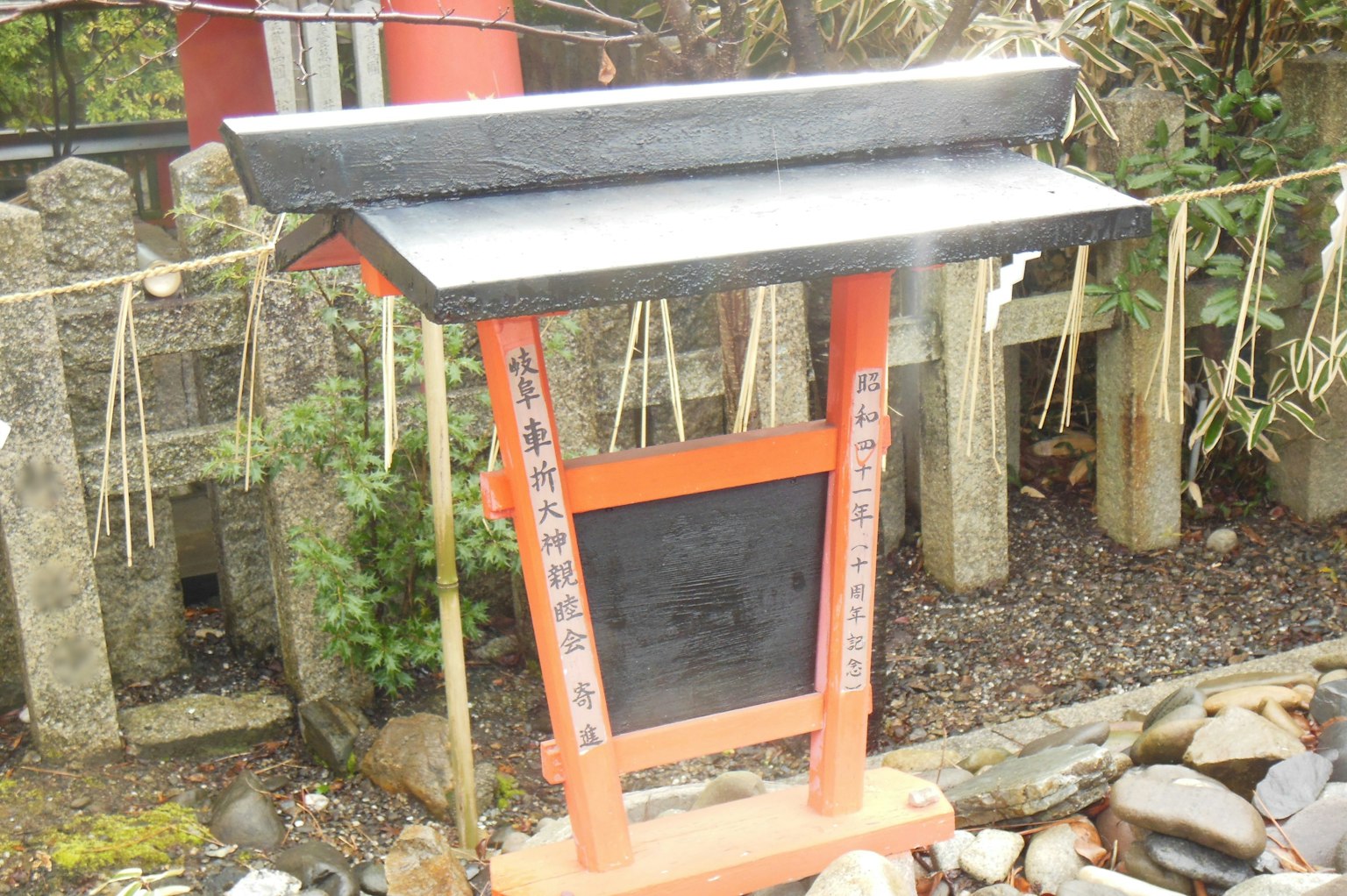 Imagen de un cartel negro cerca de una puerta torii roja