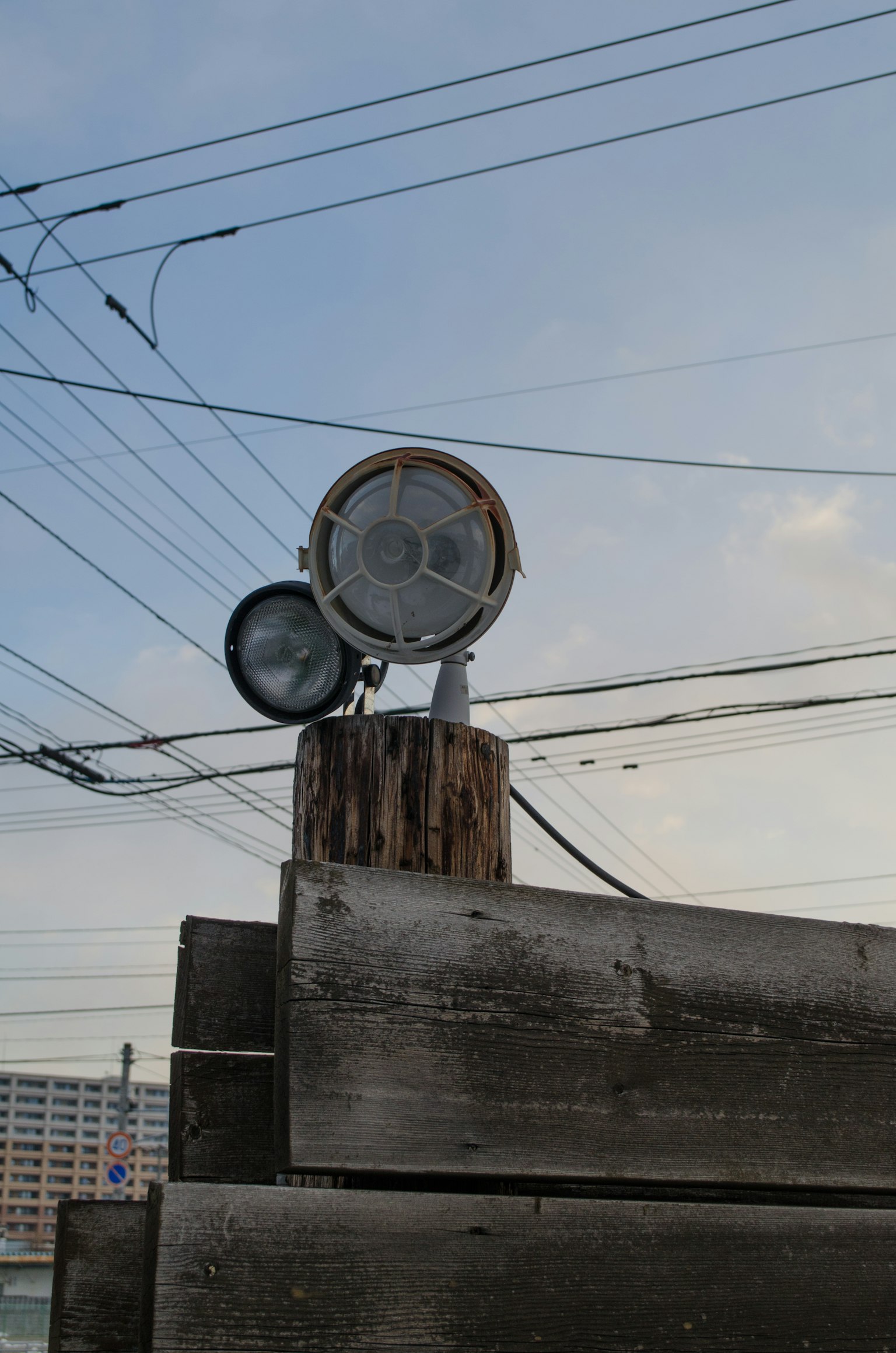 전선이 배경에 있는 나무 기둥에 장착된 두 개의 조명