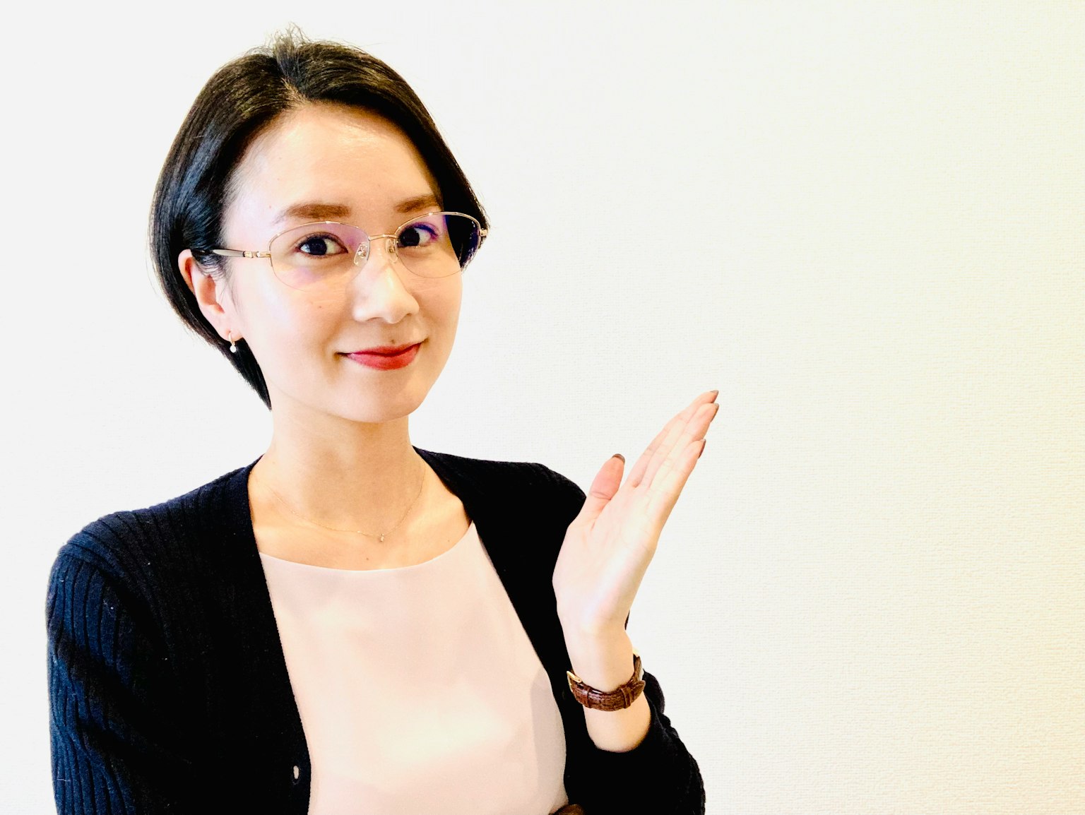 一位女性在简单背景前微笑并用手做手势
