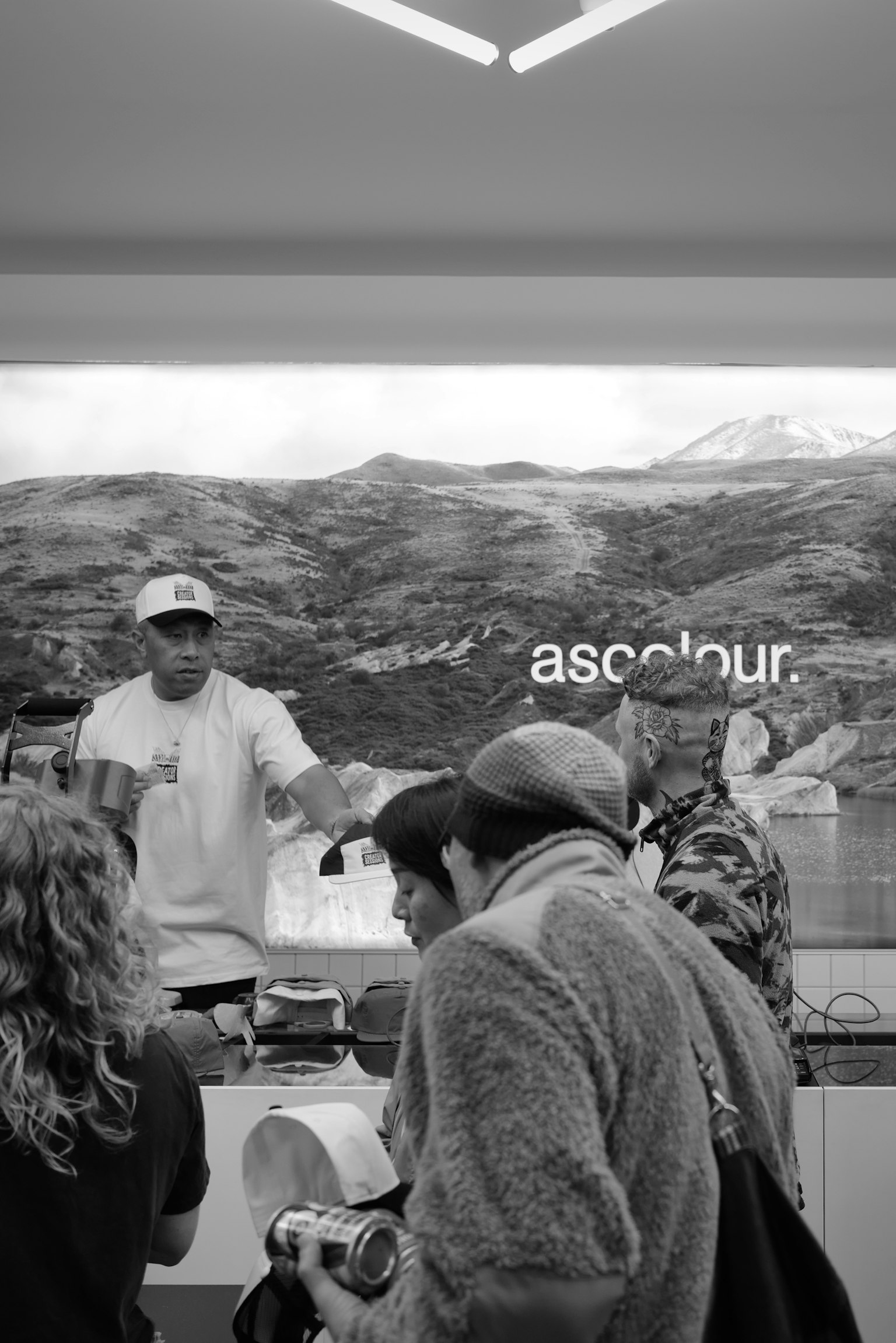 People selecting items at a counter with a mountain landscape in the background in black and white