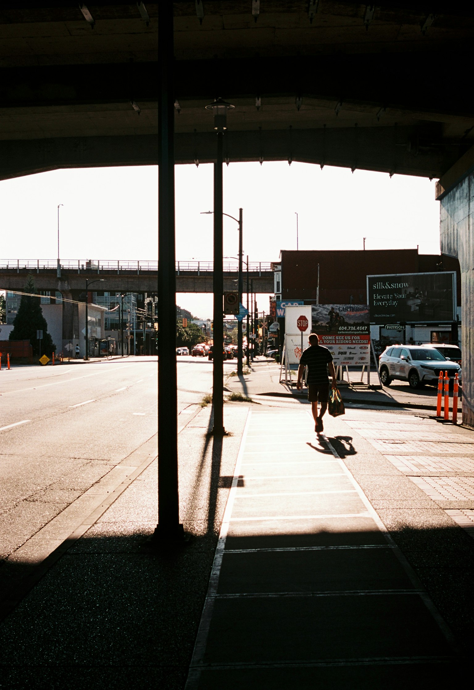 日差しの中を歩く人影と影が交差する街の風景