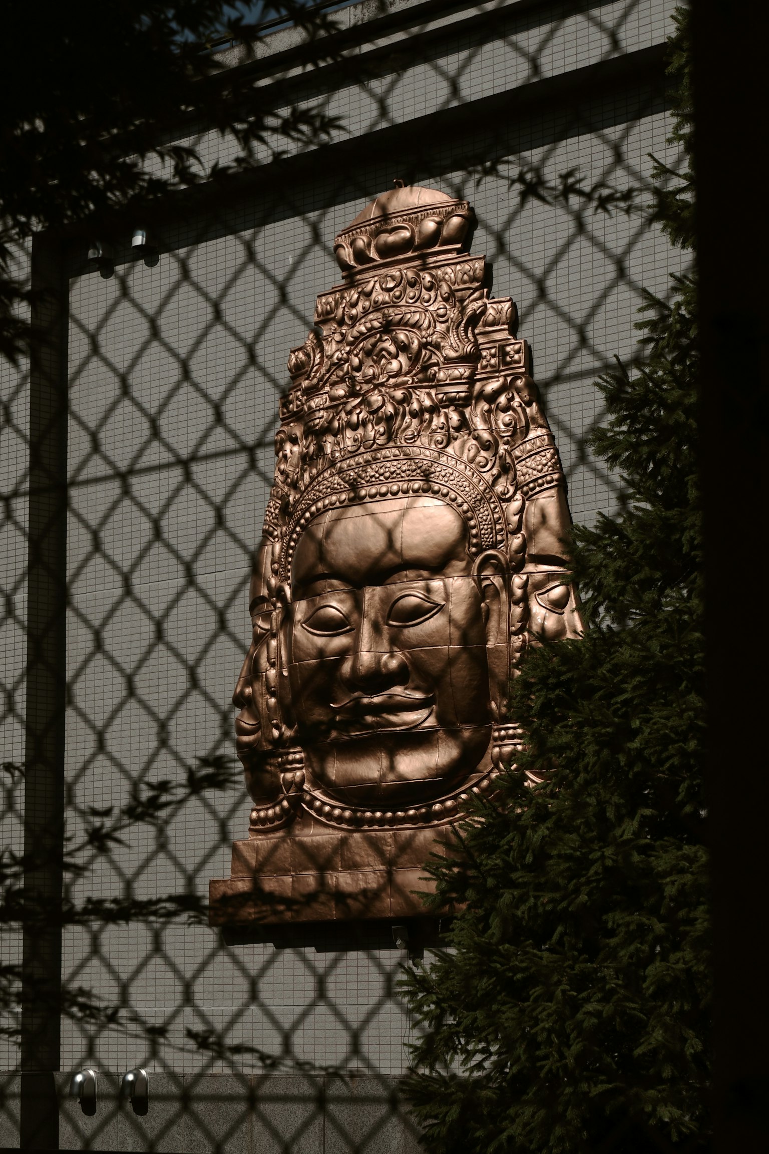 金色の仏像がフェンス越しに見える風景
