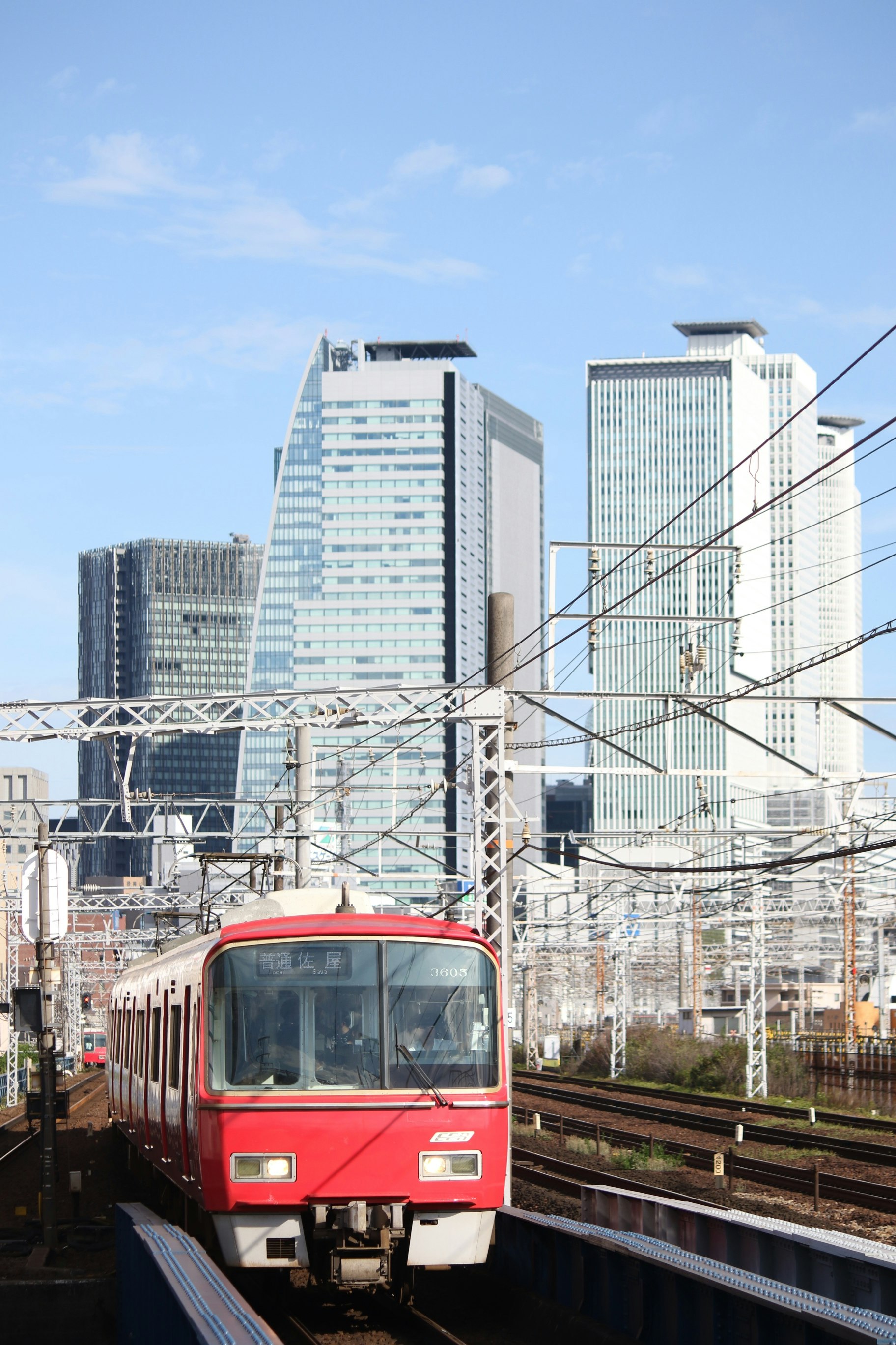 高架線路を走る赤い電車と都市のビル群