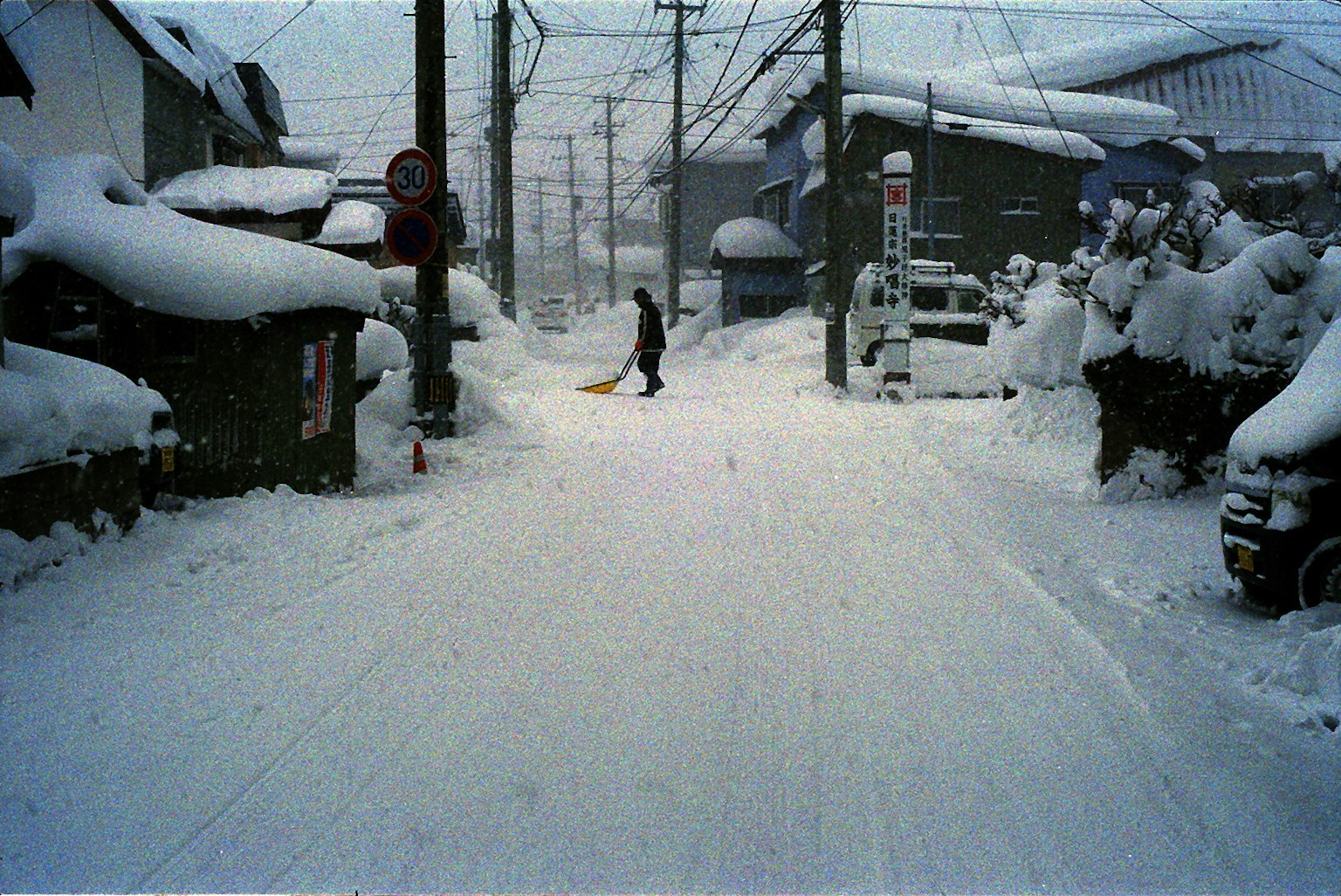 Une personne déneigeant une rue étroite recouverte de neige