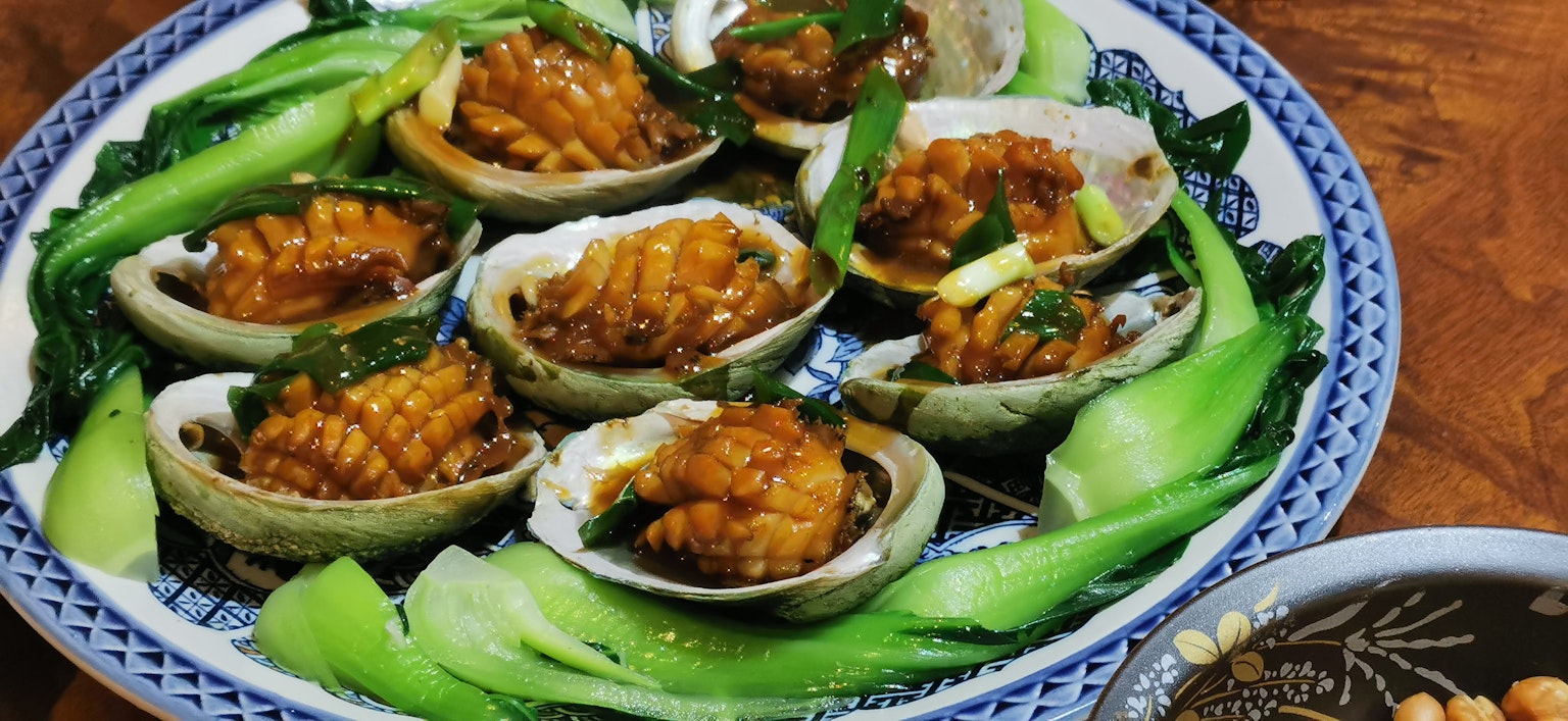 Piring hidangan abalon yang disajikan dengan bok choy