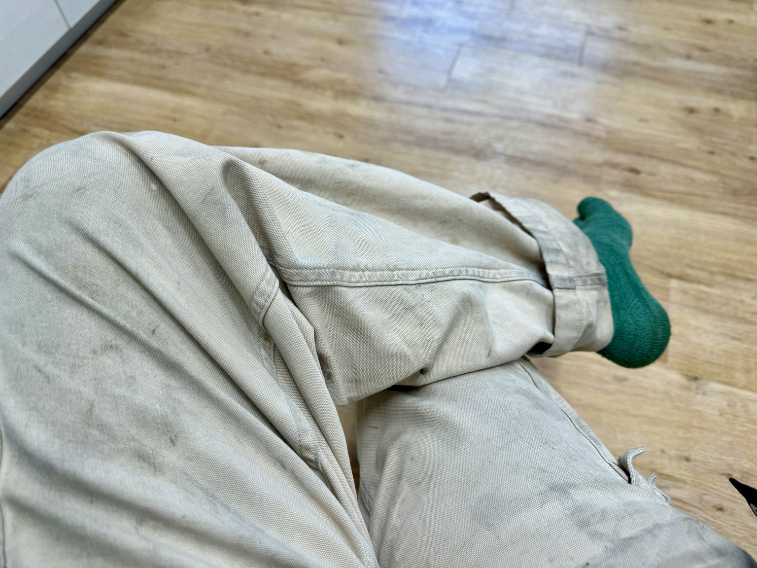 Foto di una gamba che indossa pantaloni bianchi sporchi e un calzino verde