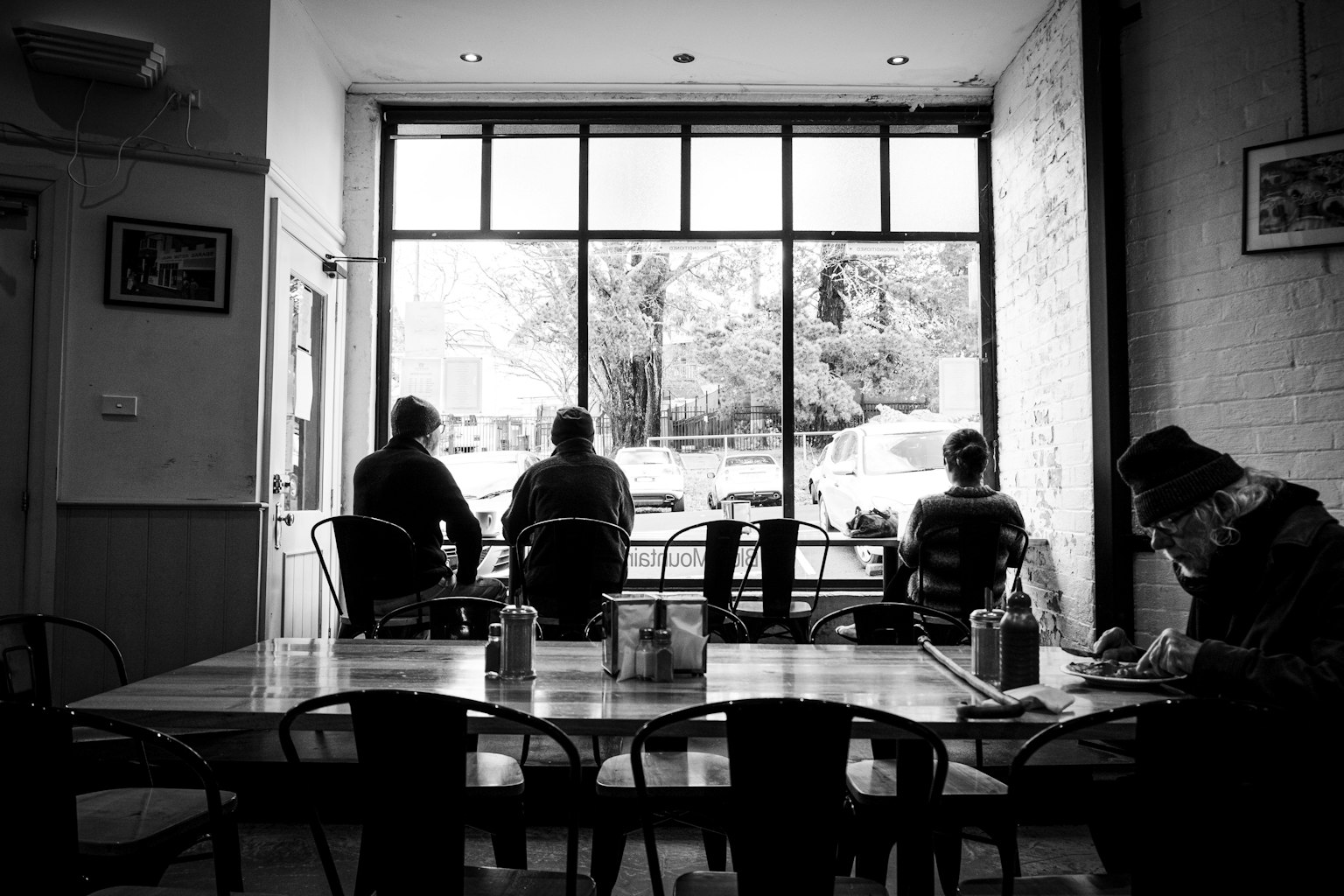Silhouettes of people sitting by a café window with a table setting