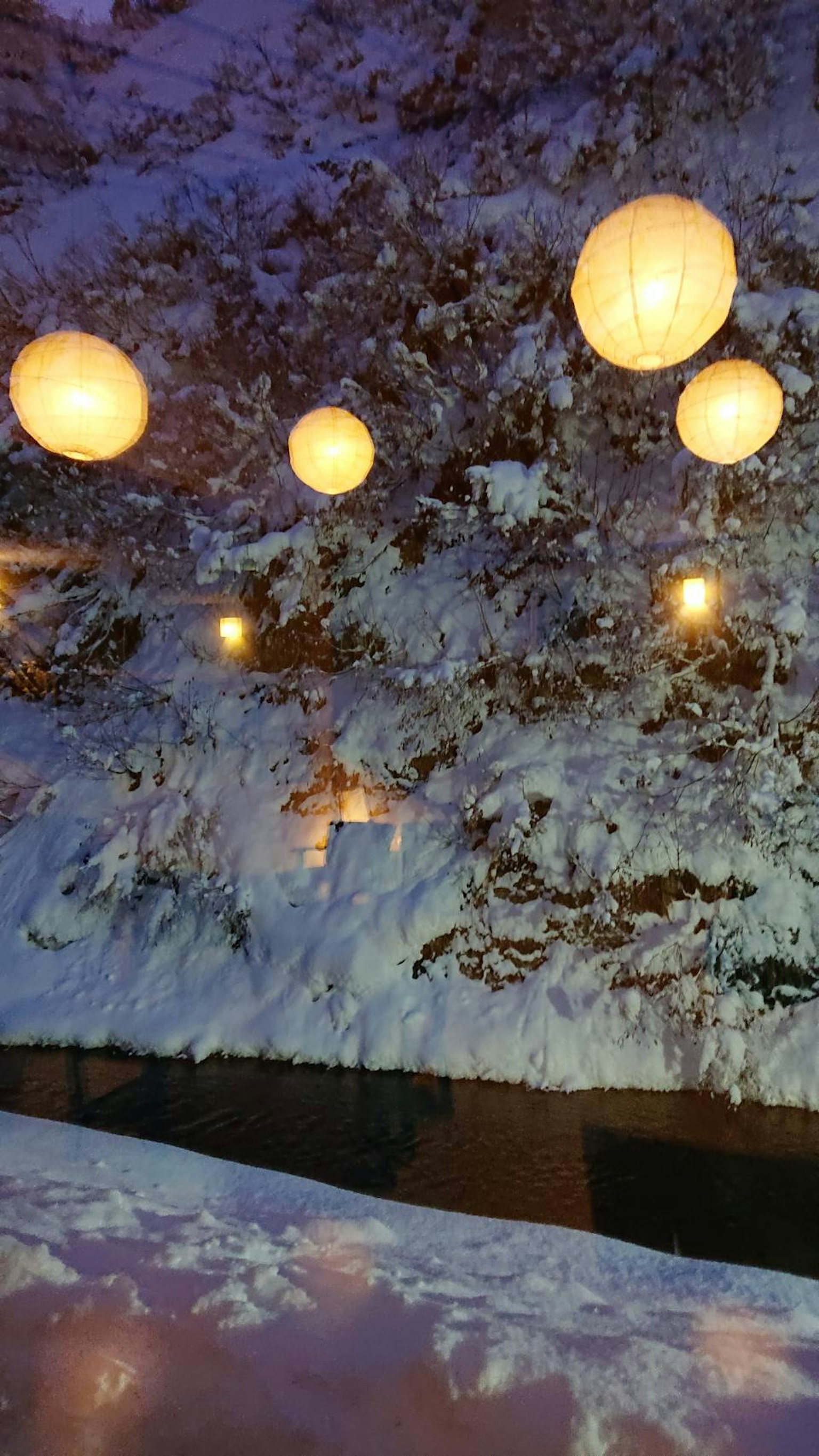 Lanterns caldi che galleggiano su un paesaggio innevato