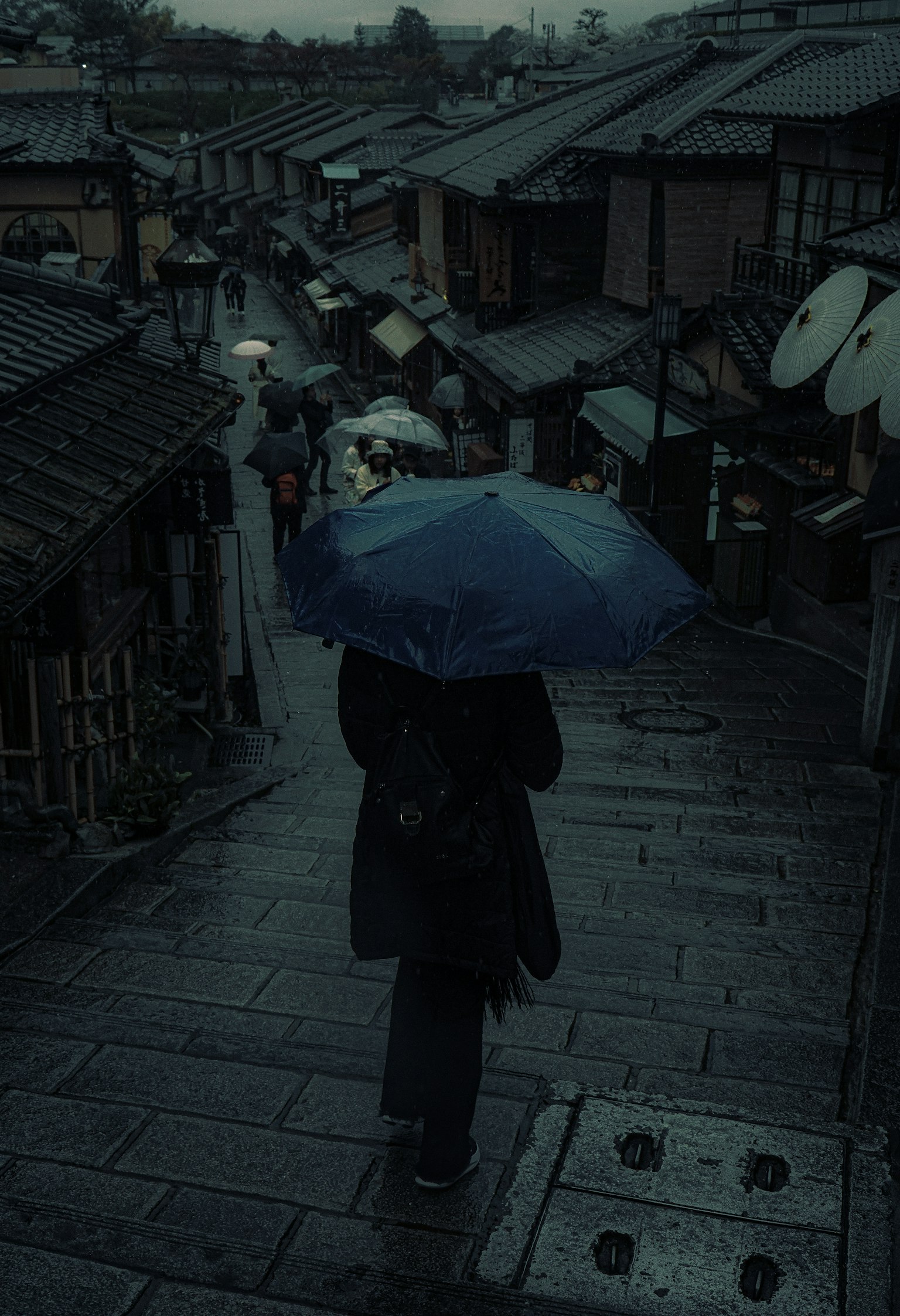 一个人在雨中走在历史街道上，手持雨伞