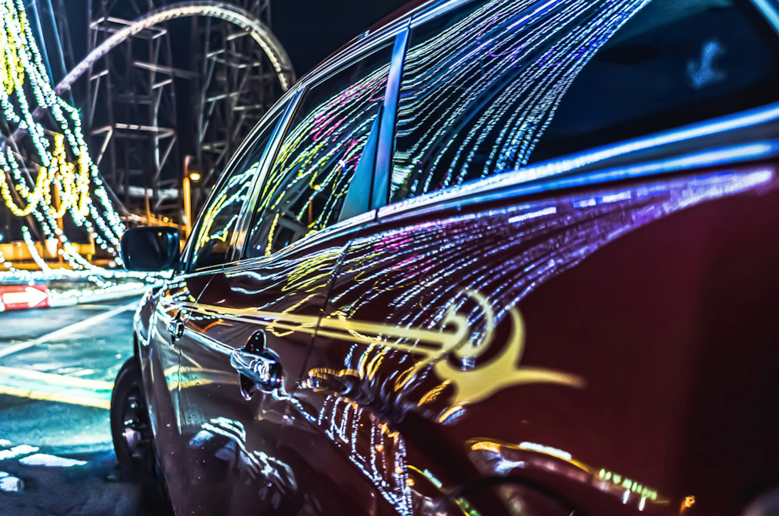 Rotes Auto spiegelt bunte Lichtspuren bei Nacht wider