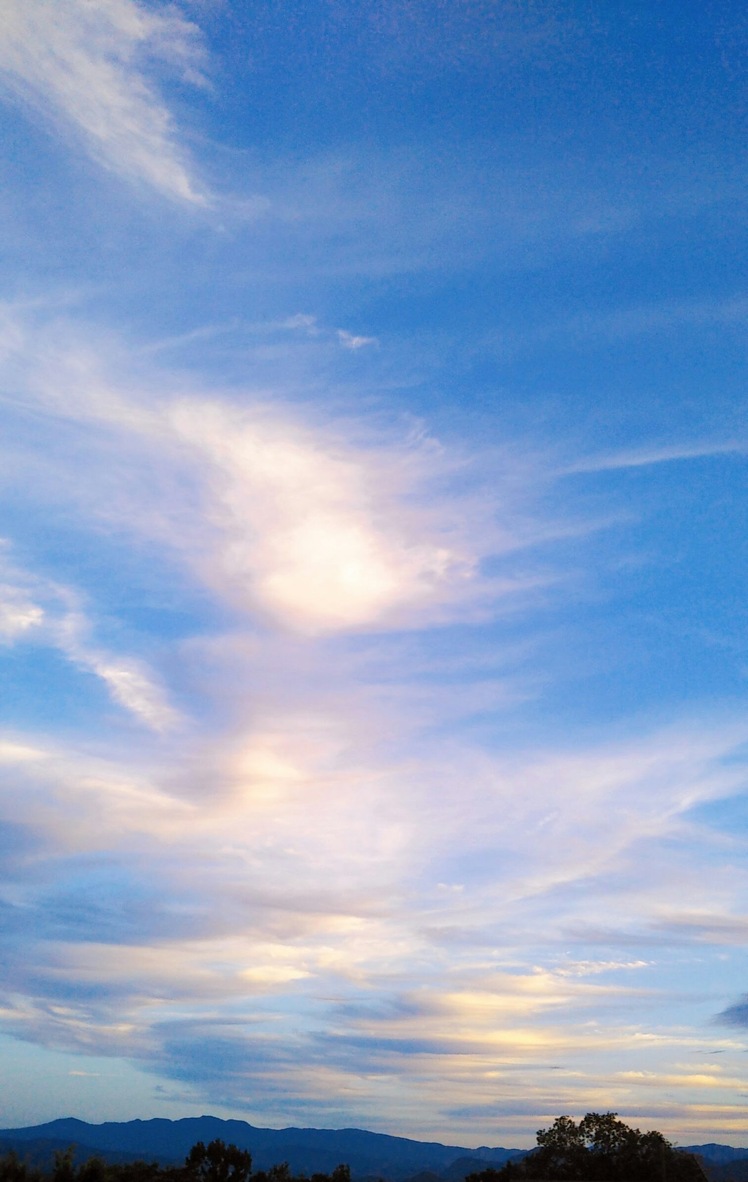 Nubes suaves se extienden a través de un cielo azul creando un paisaje sereno