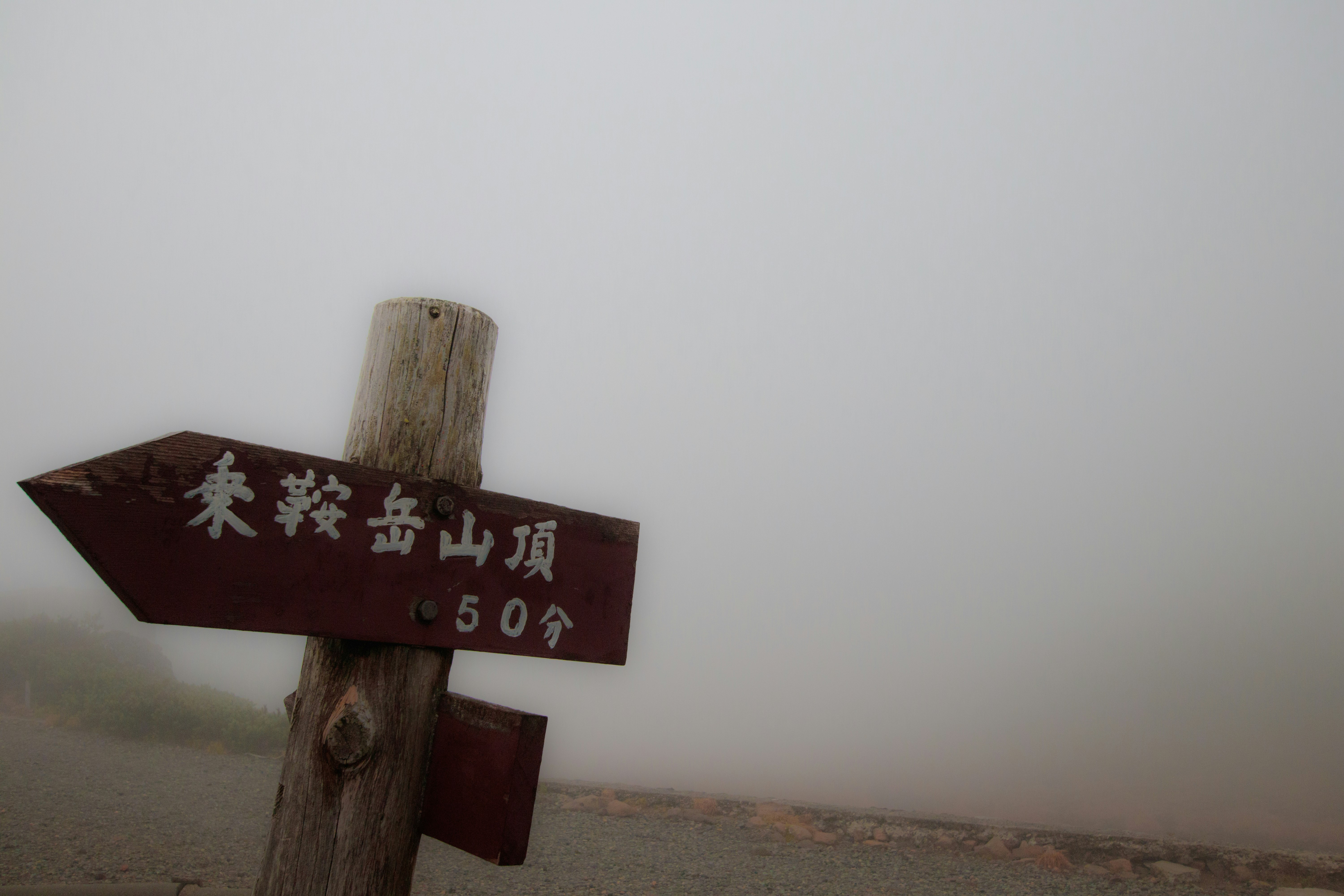 Cartello segnaletico del sentiero in cima alla montagna, nella nebbia
