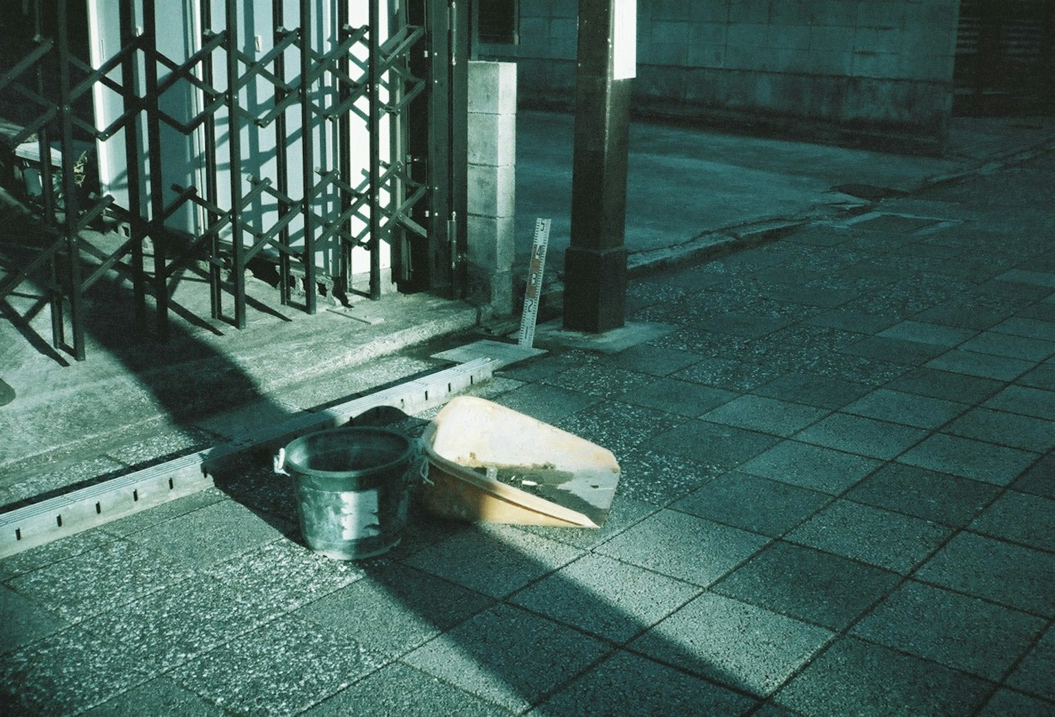 Image d'un seau en métal et d'une boîte en carton placés sur une rue faiblement éclairée
