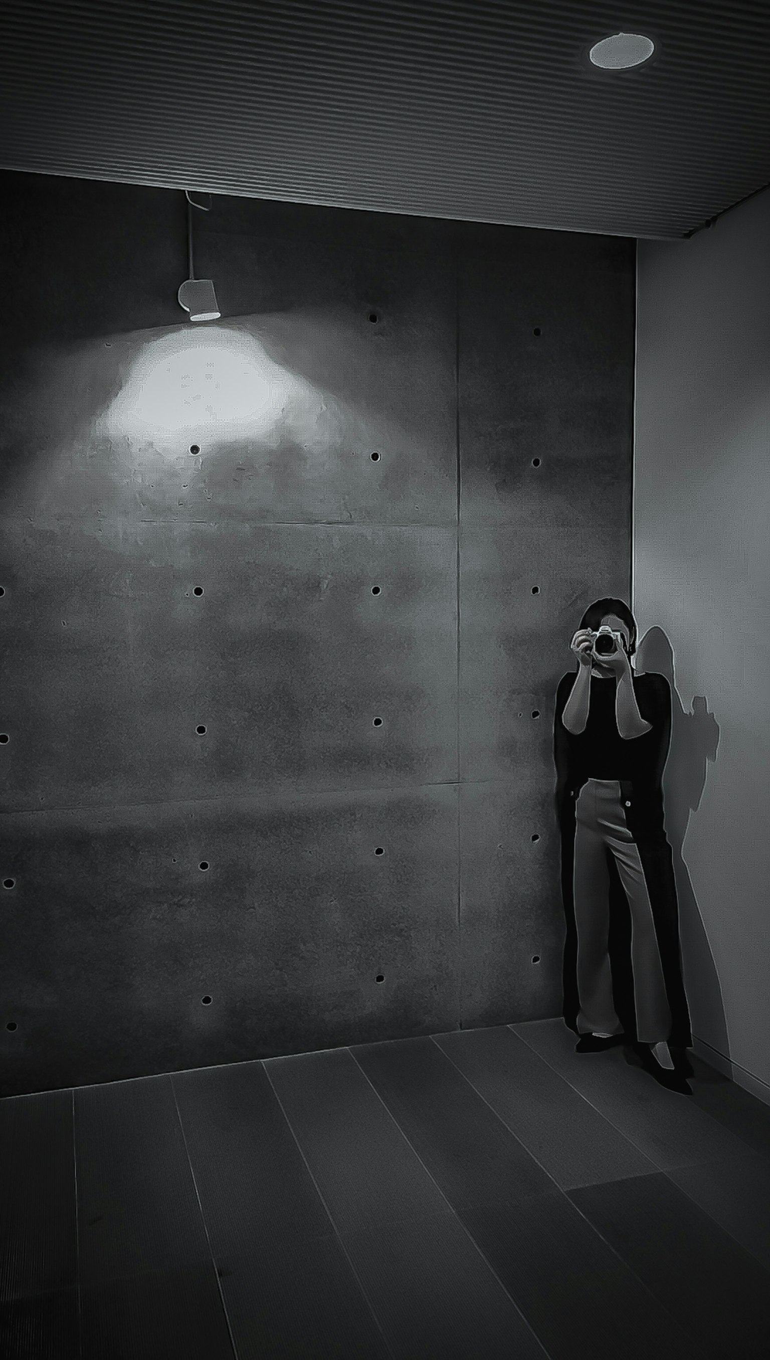 Person standing in the corner of a dark concrete wall Soft monochrome lighting creates gentle shadows