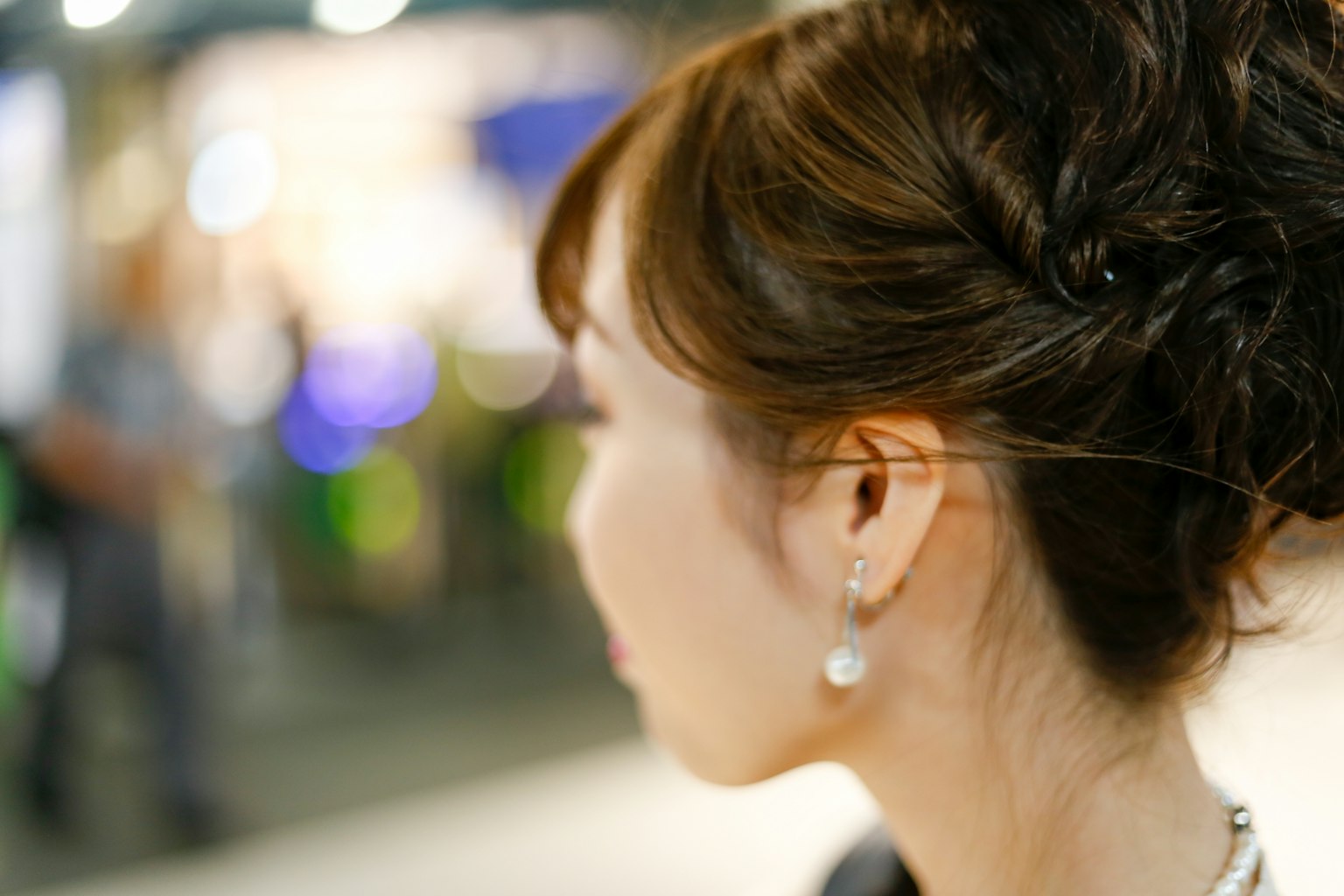 Photo d'une femme vue de dos avec une coiffure en chignon et des boucles d'oreilles en perles