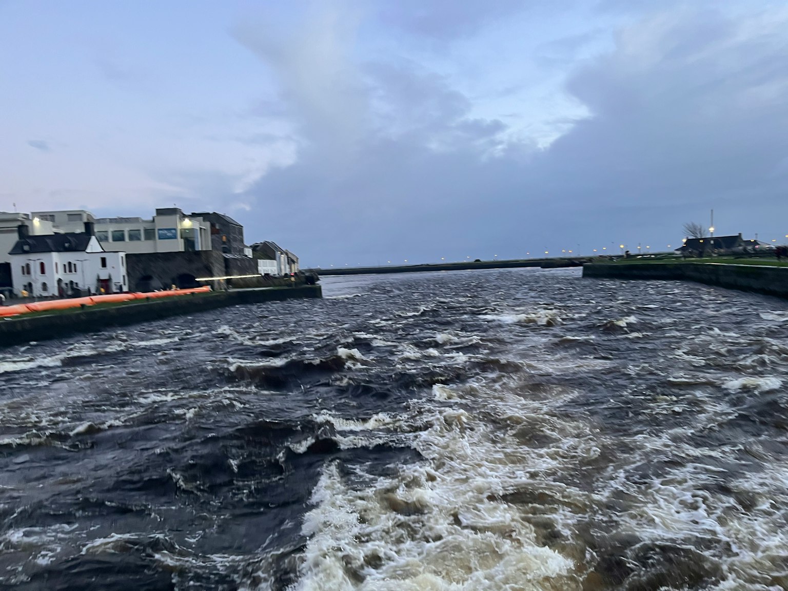 View of a turbulent river with buildings along the shore