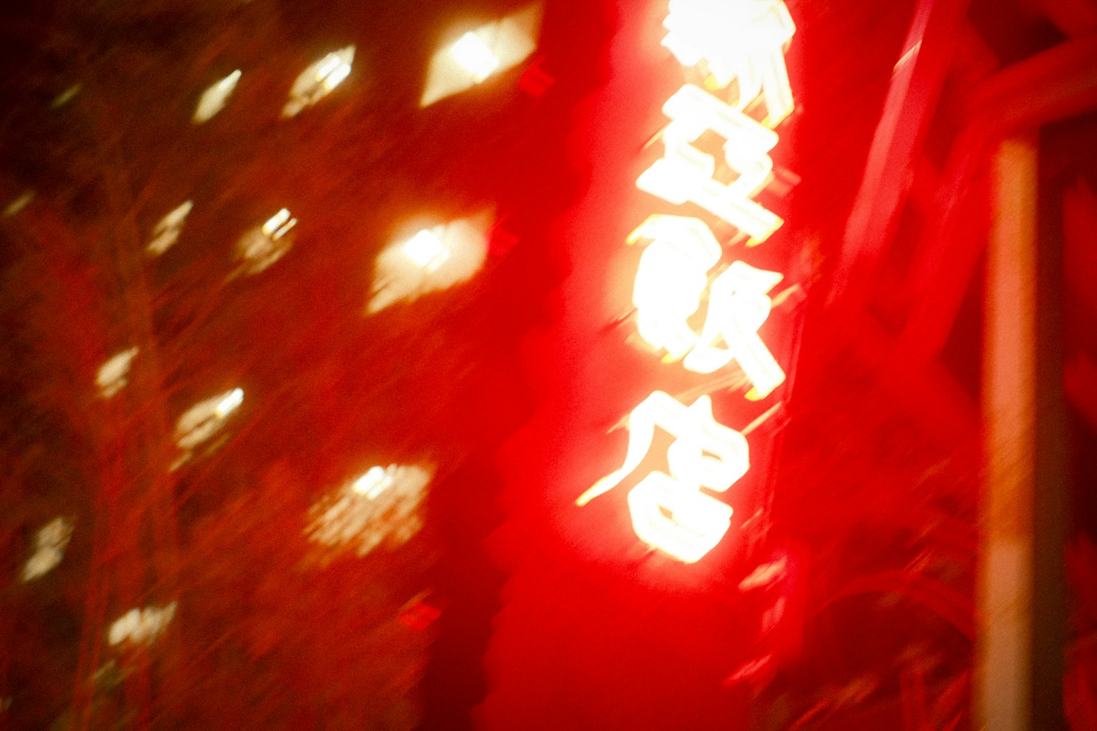 Verschwommenes rotes Neonzeichen in einer nächtlichen Stadtlandschaft