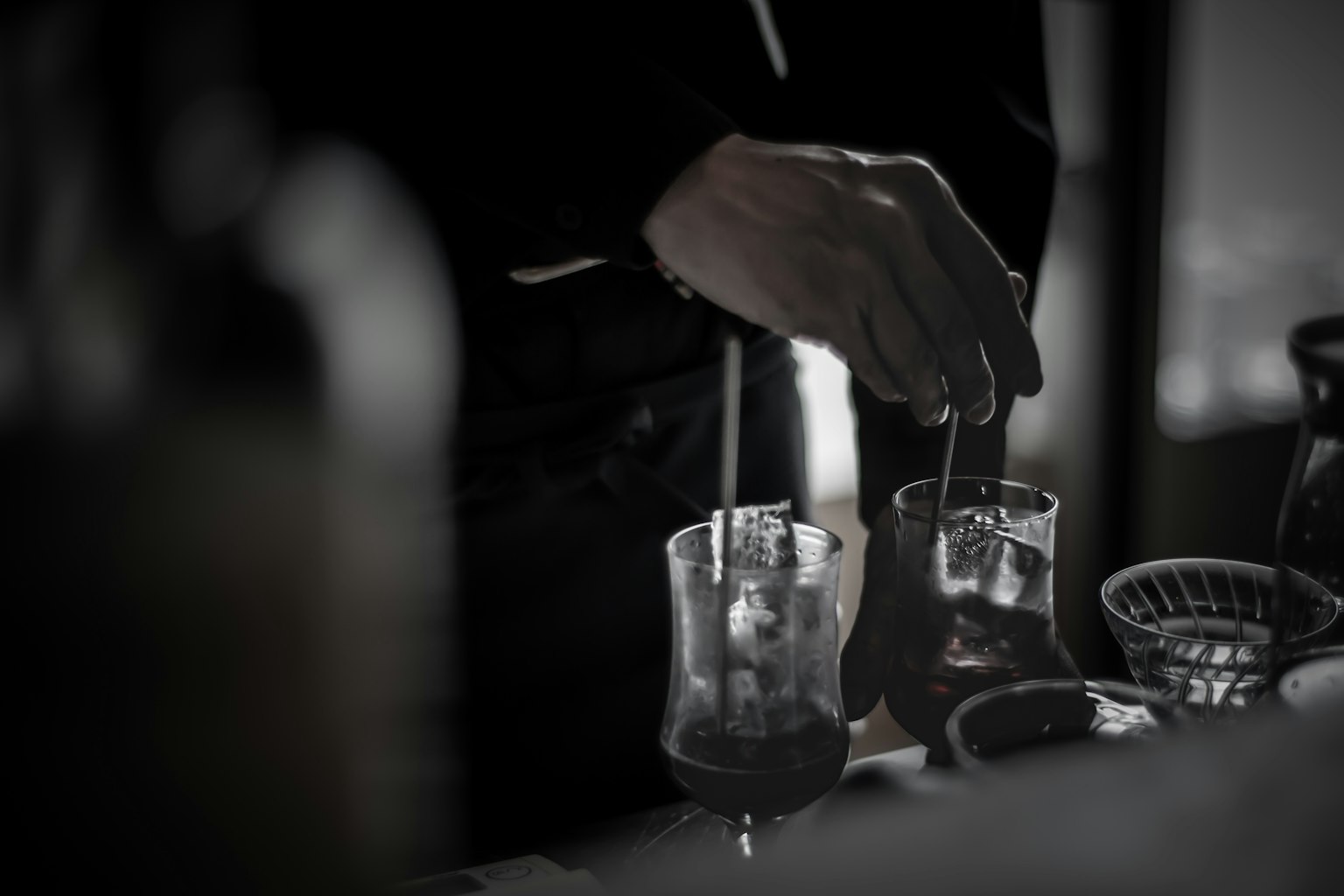 酒吧中調製雞尾酒的手特寫，具有戲劇性的黑白色調