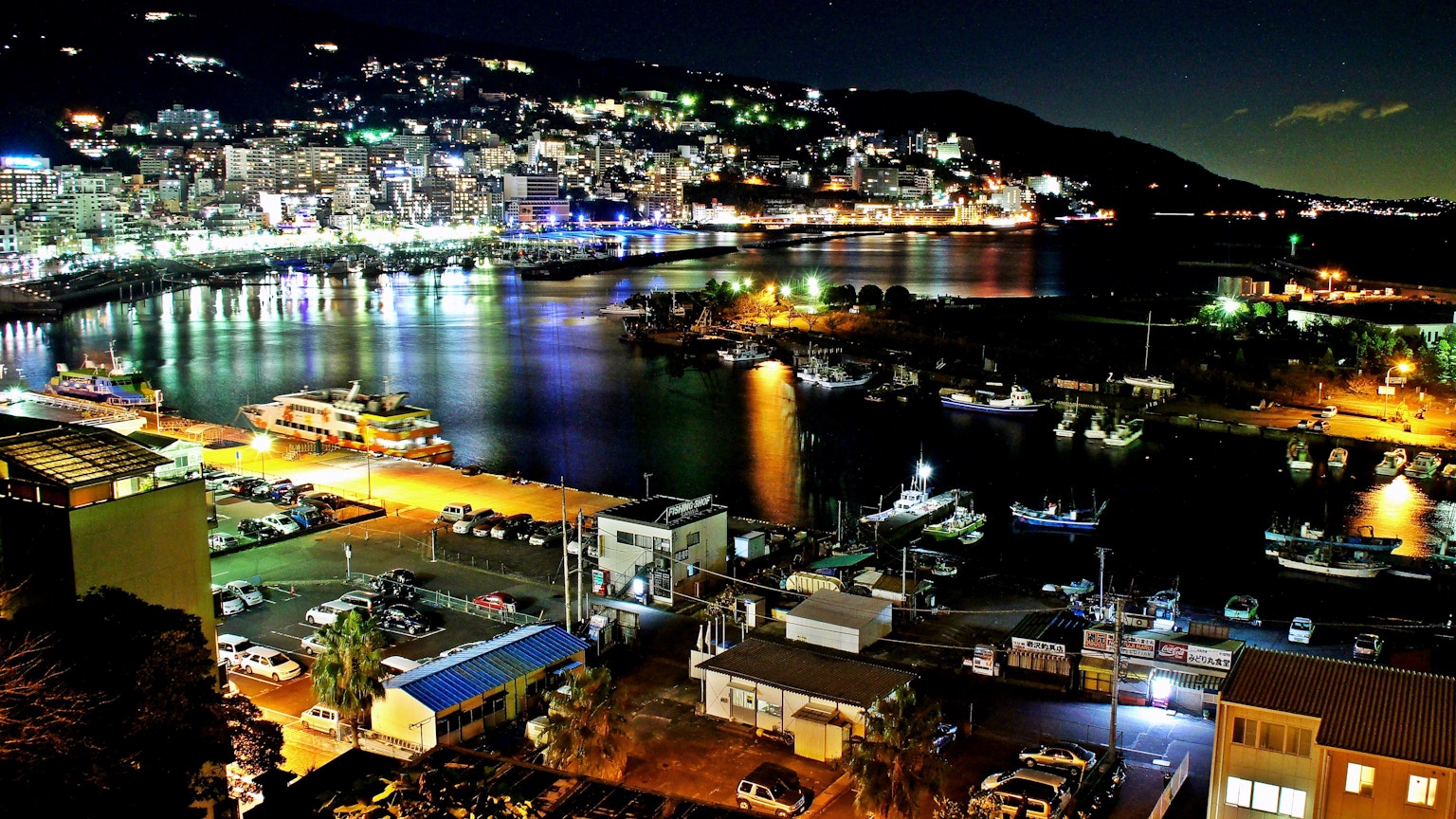 Magnifique vue nocturne d'une ville portuaire avec des bateaux et des bâtiments illuminés par des lumières colorées