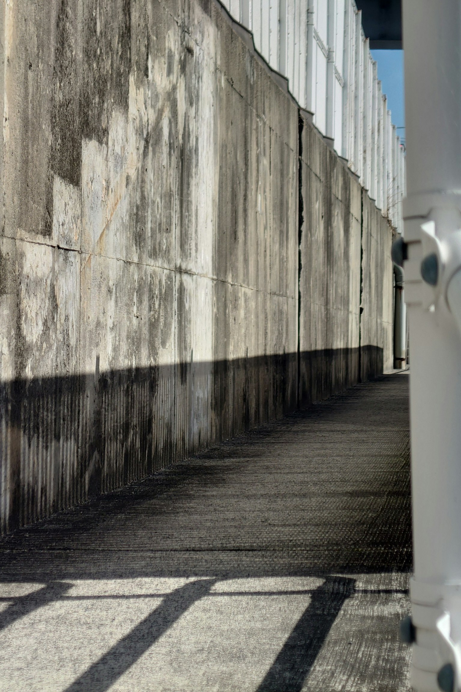 Ein Gehweg mit Schatten, die von einer alten Wand geworfen werden